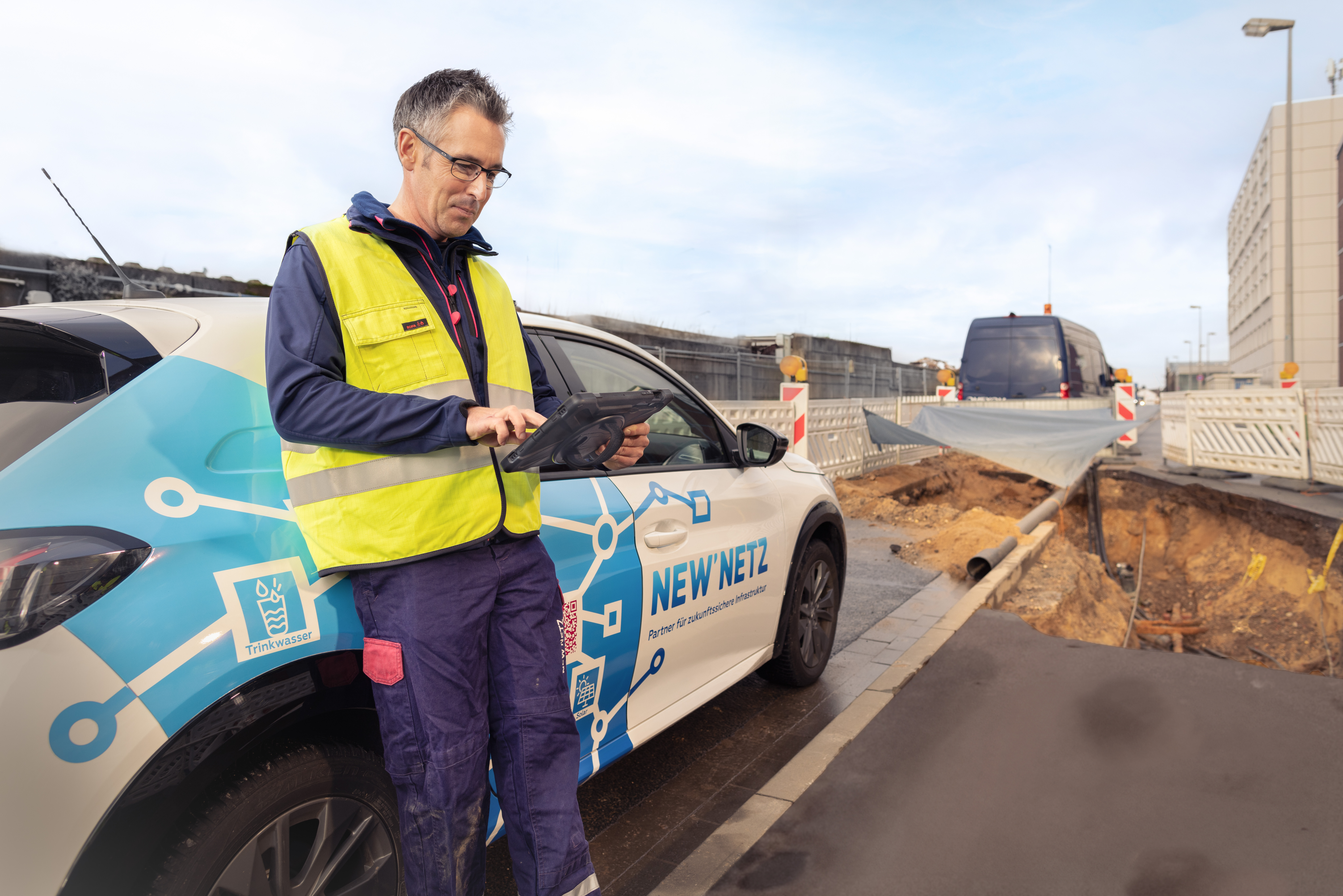 Installateur befindet sich auf einer Baustelle und informiert sich mit seinem Tablet über technische Richtlinien.