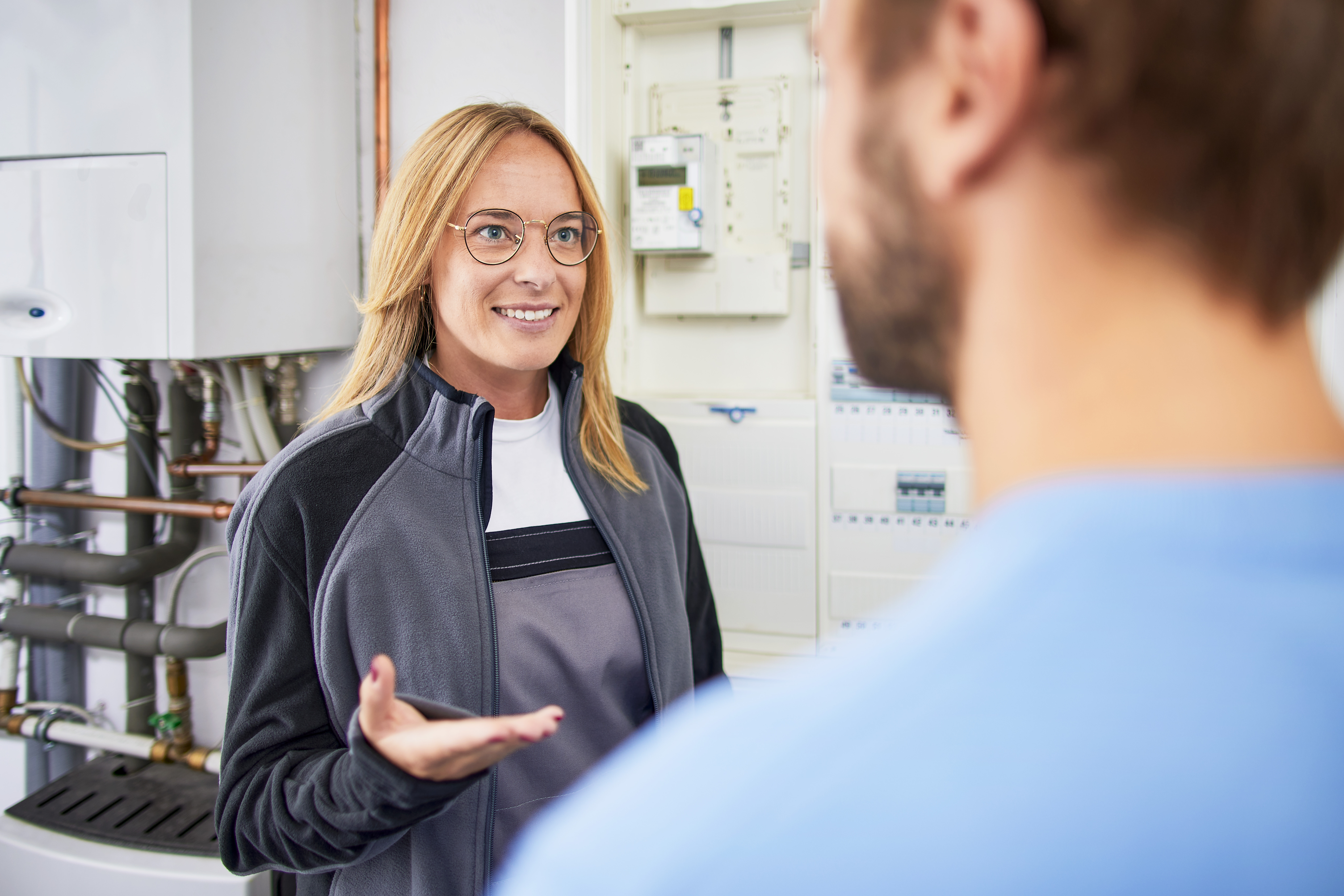 Installateurin berät einen Kunden über eine Wärmepumpe