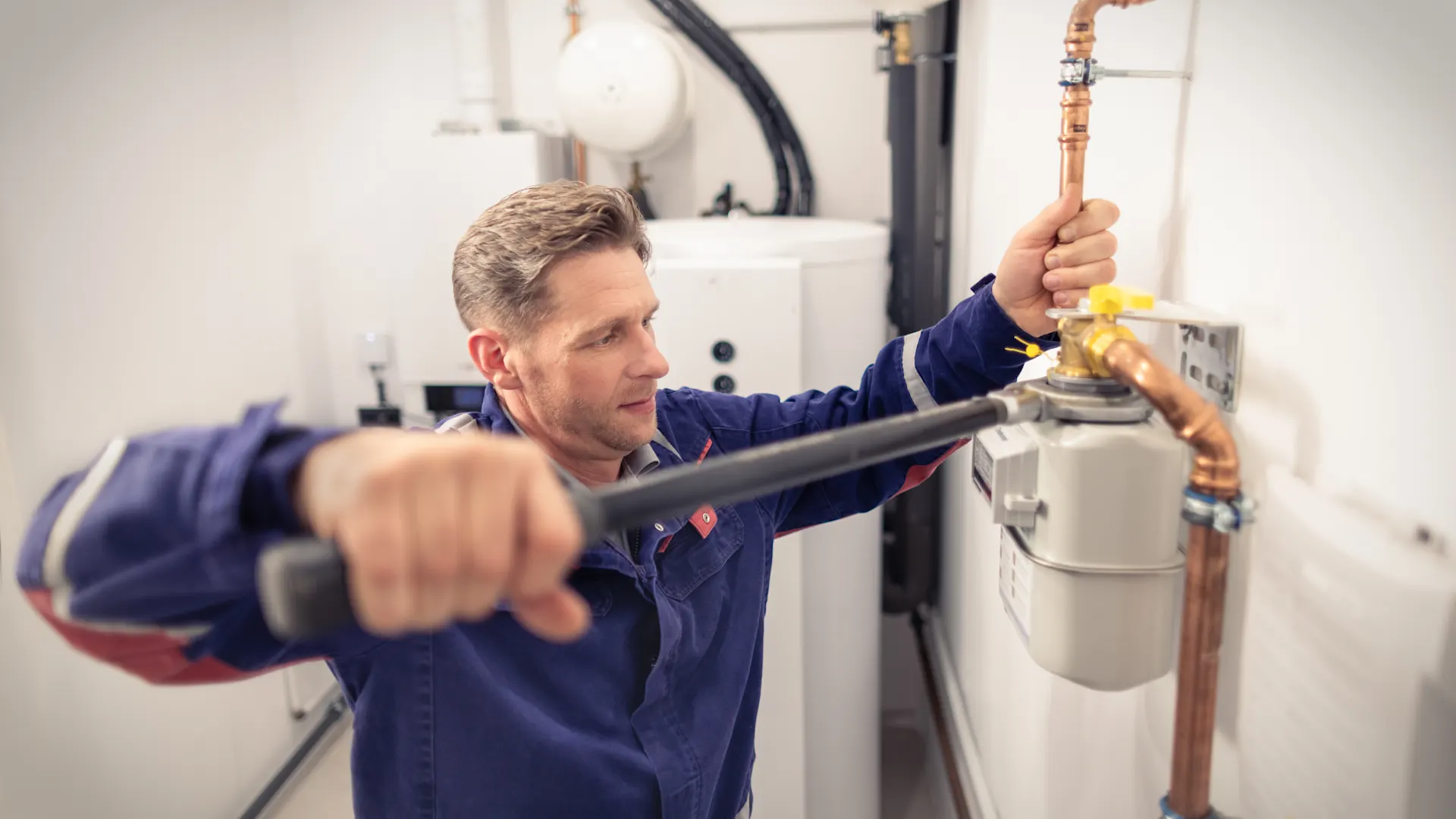 Installateur stellt die Erdgasversorgung sicher Ein Installateur arbeitet am Erdgaszähler und stellt die Erdgasversorgung sicher