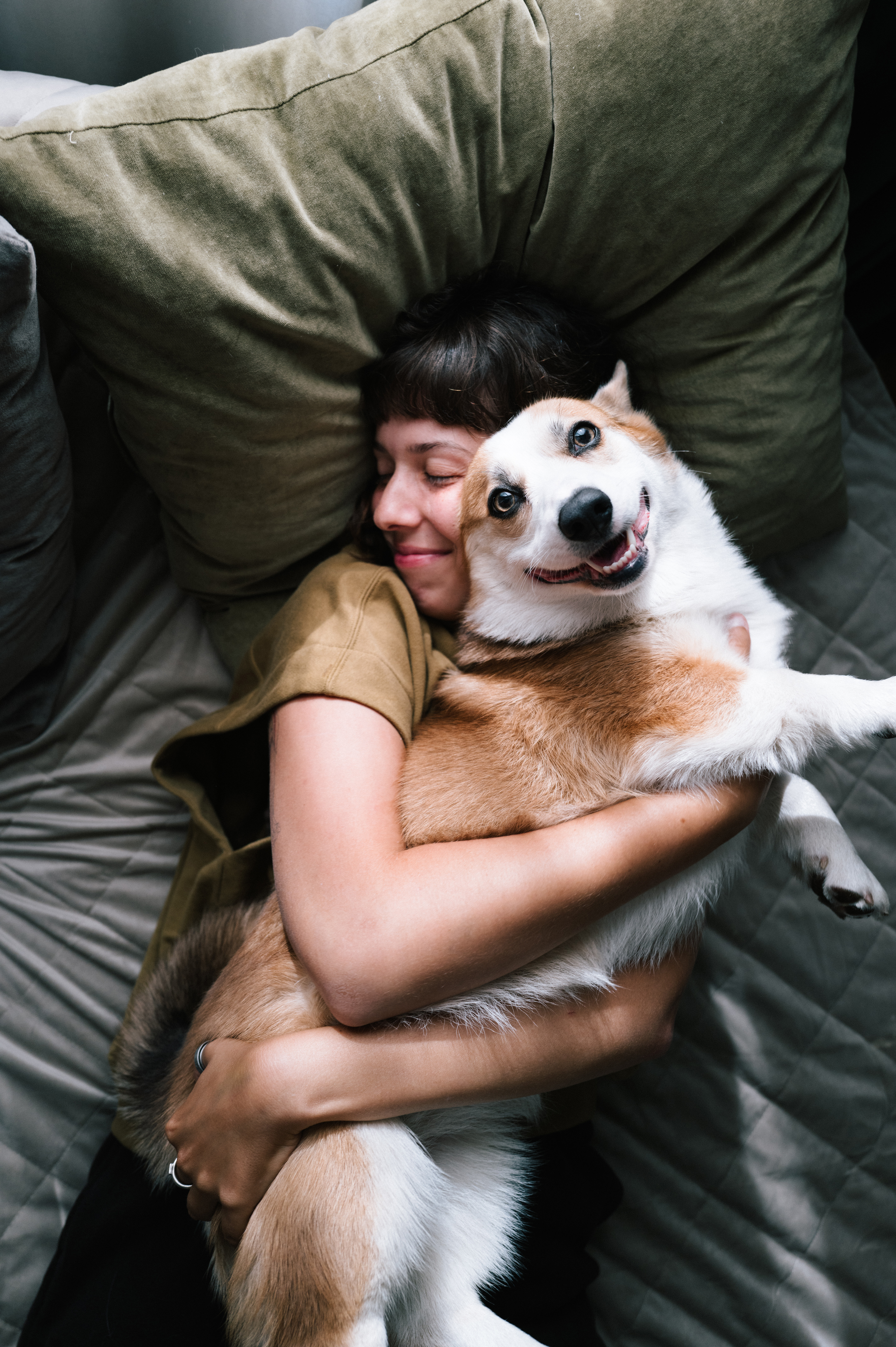 Eine Frau liegt mit ihrem Hund im Bett. Sie ist zufrieden mit der NEW Energie, als erfahrenen Energieversorger in der Region.