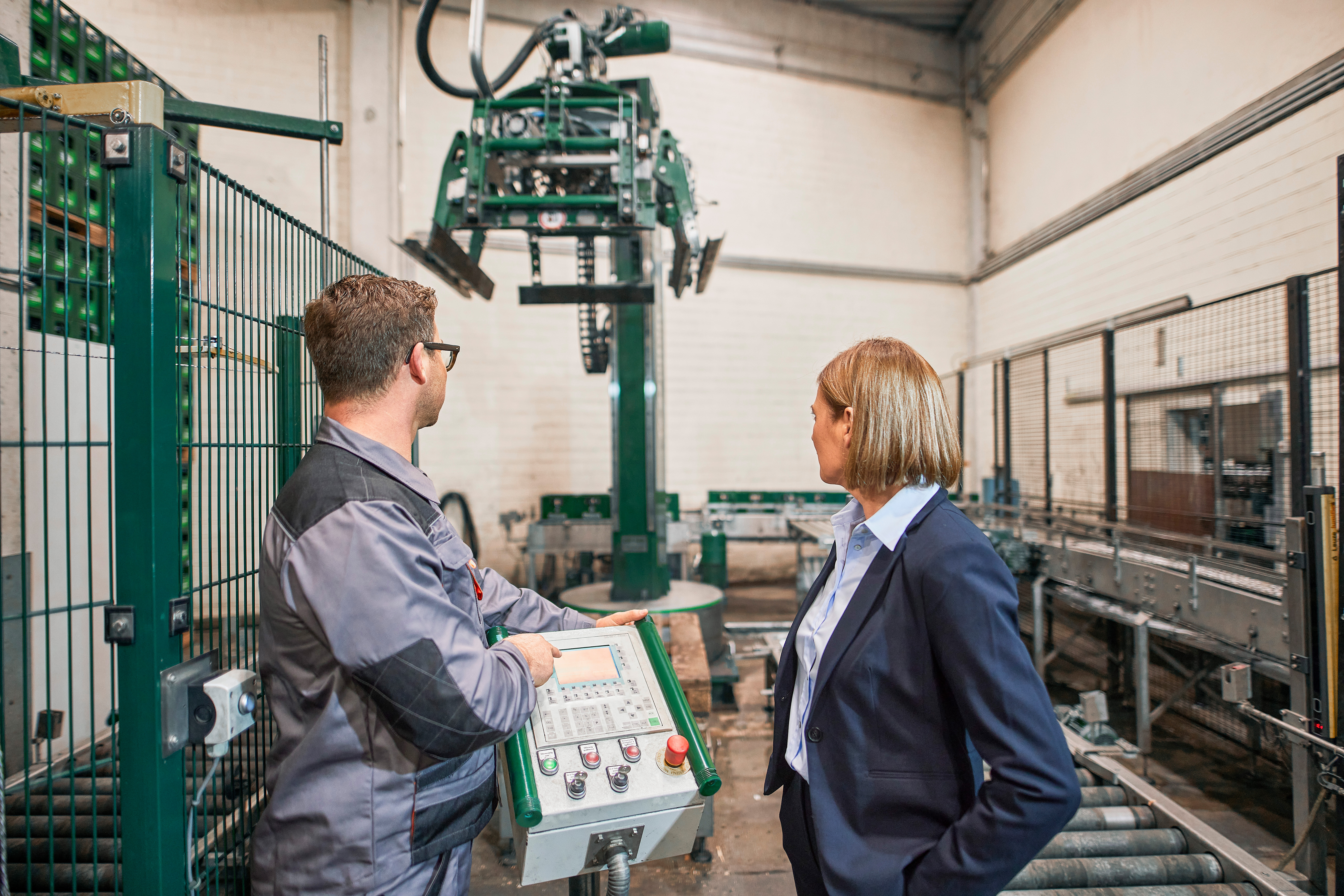 Ein Mitarbeiter in einem Brauhaus zeigt die Funktion eines Palettieres mit Industriestrom seiner Geschäftsführerin.