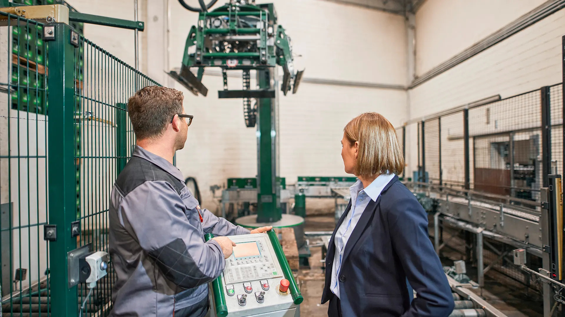 Funktion eines Palettieres mit Industriestrom Ein Mitarbeiter in einem Brauhaus zeigt die Funktion eines Palettieres mit Industriestrom seiner Geschäftsführerin.