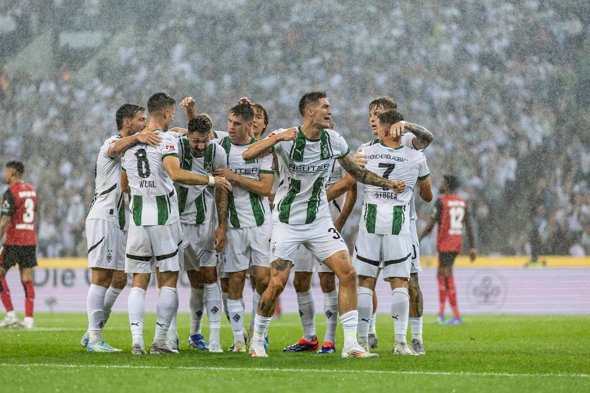 Mehrere Fußballspieler im weißen Trikot von Borussia Mönchengladbach jubeln nach einem Tor.