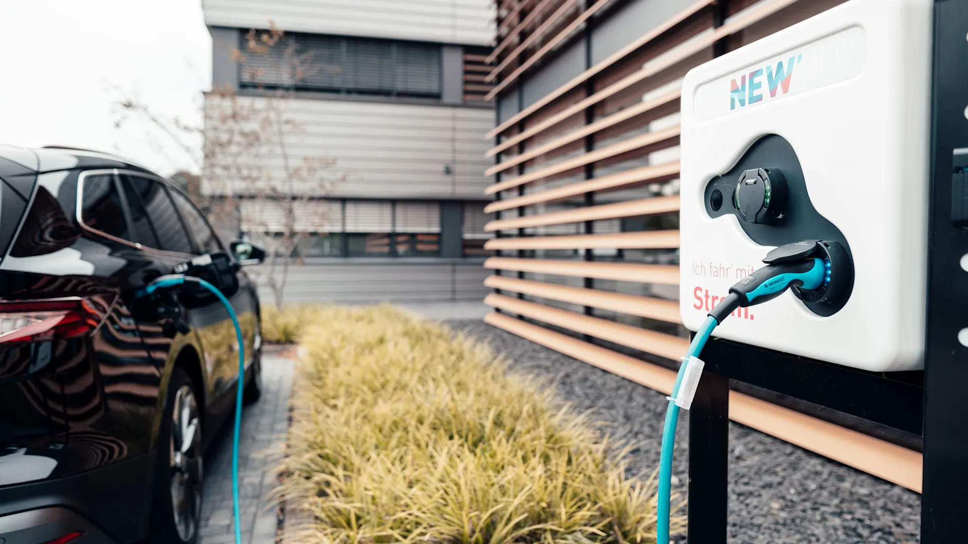 Firmenwagen lädt an Ladesäule Firmenwagen wird auf einem Firmengelände an einer Ladesäule der NEW Energie geladen.