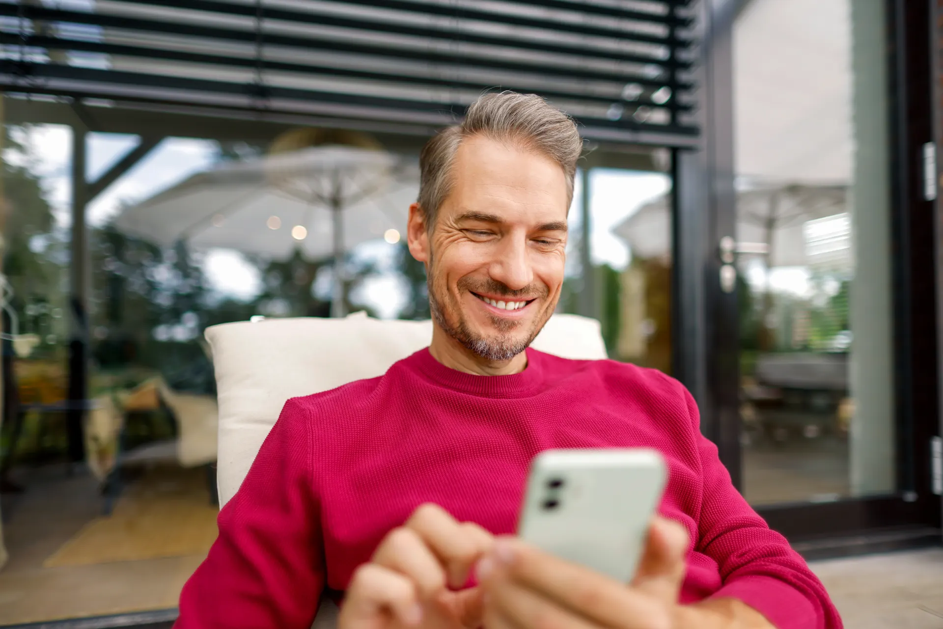 Der Mann liegt mit seinem Smartphone im Liegestuhl und vergleicht die Preise.