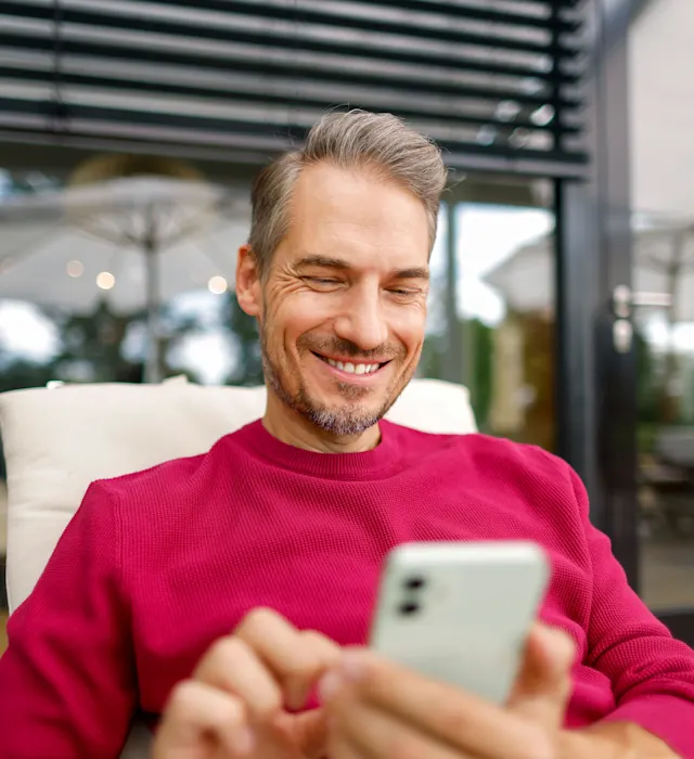Mann mit Smartphone vergleicht Preise Ein Mann liegt mit seinem Smartphone im Liegestuhl im Garten und vergleicht die Preise der NEW Energie.