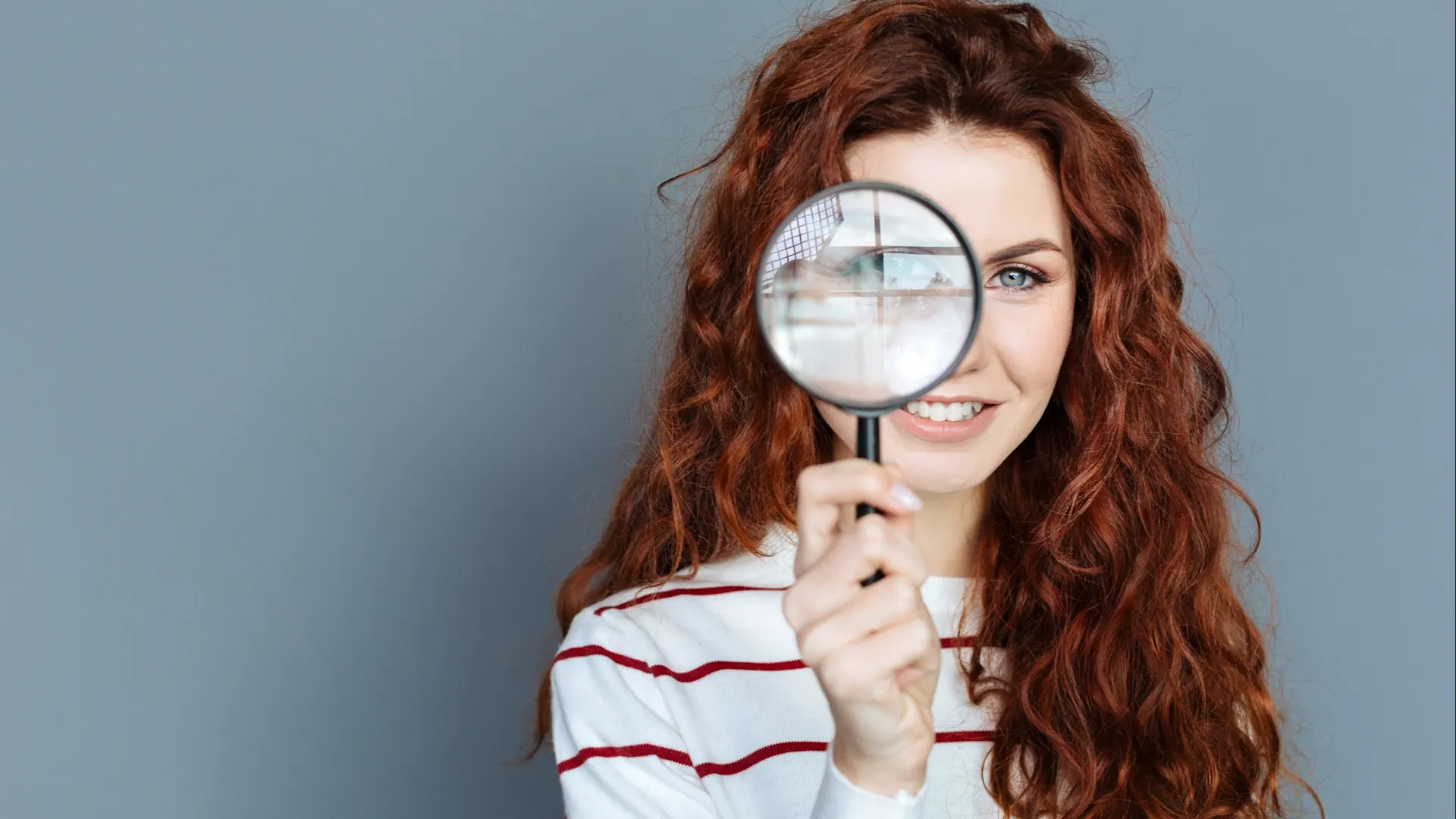 Frau mit Lupe interessiert sich für die NEW Energie Eine Frau schaut durch eine Lupe und prüft die Angebote von der NEW Energie.