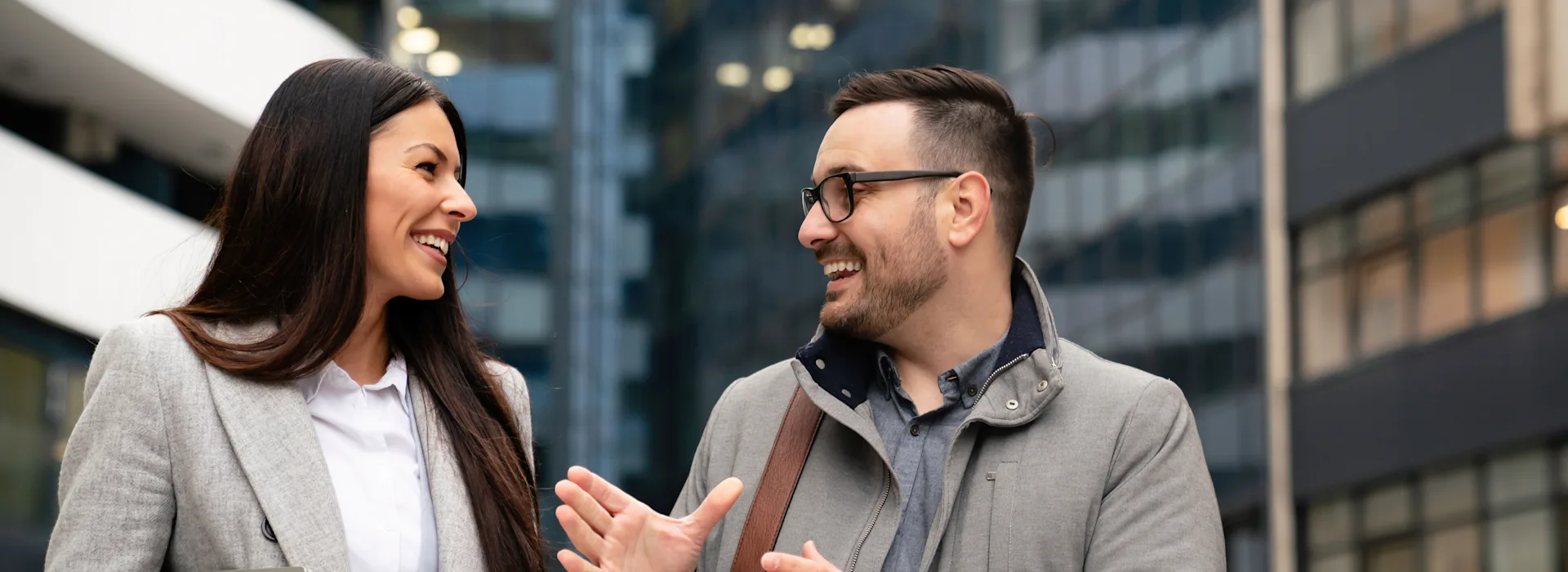 Kollegen unterhalten sich über günstige Energie Ein Mann und eine Frau unterhalten sich vor einem Bürogebäude.