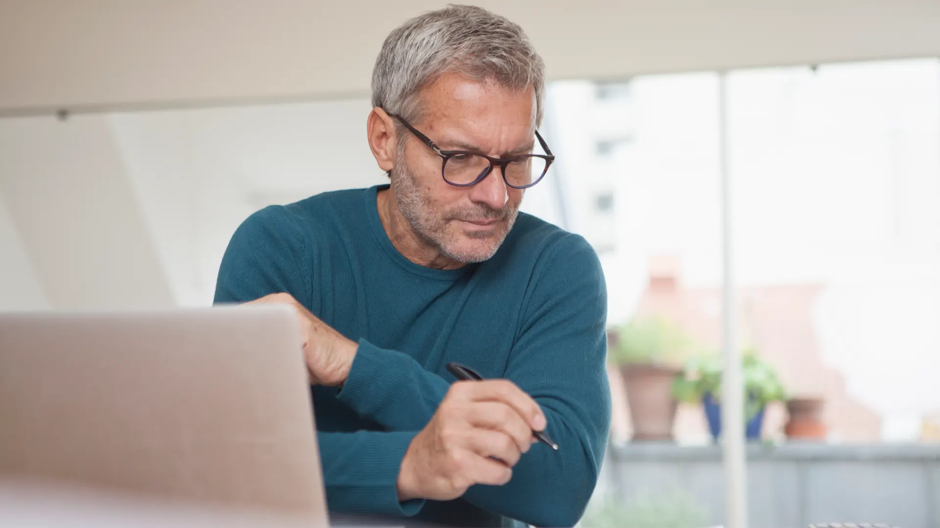 Mann an Laptop Ein Mann sitzt an einem Tisch und vergleicht am Laptop Tarife der NEW Energie.