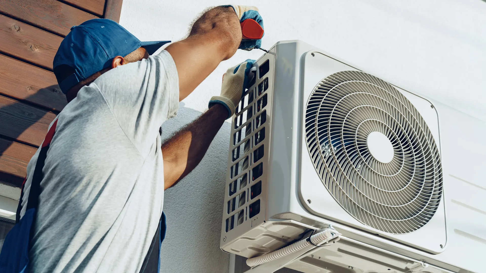 Split-Klimaanlage Ein Mann schraubt an der Außeneinheit einer Split-Klimaanlage herum.