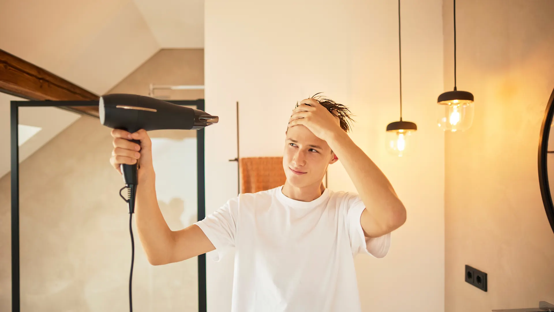Haare föhnen mit Ökostrom Ein junger Mann föhnt sich die Haare mit Ökostrom, welcher günstigen Strom von dem Stromanbieter NEW Energie darstellt.