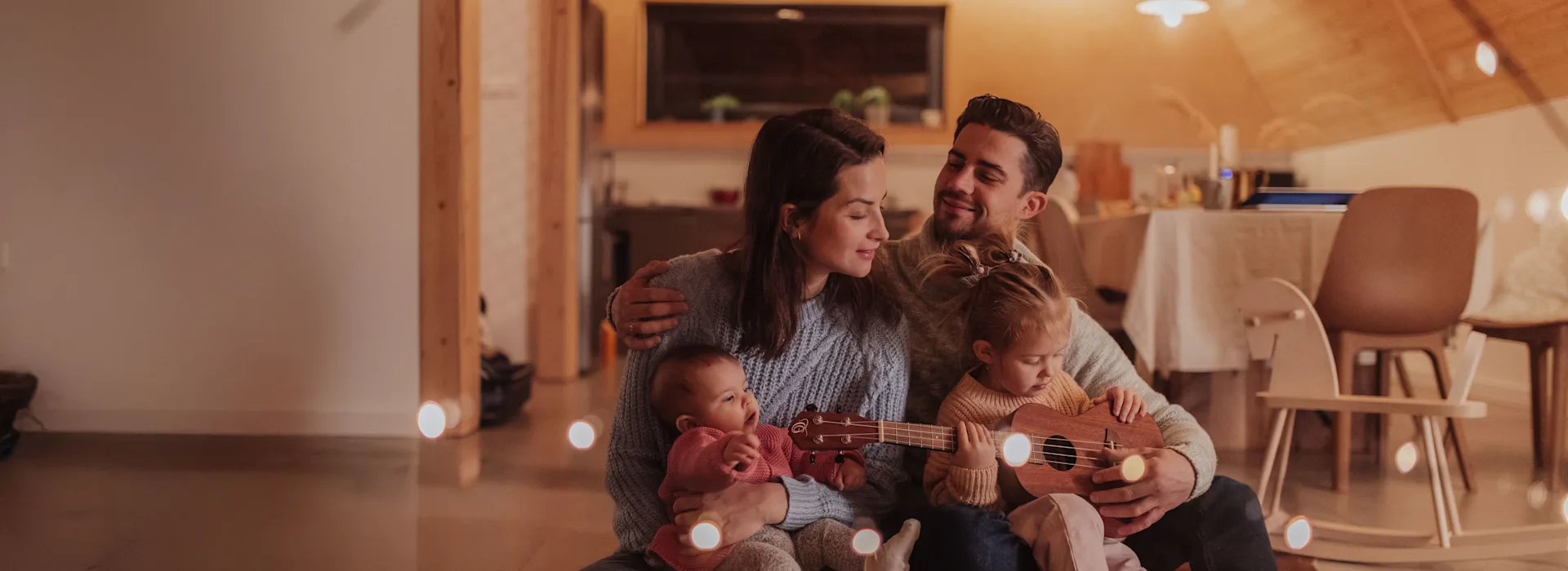 Familienzeit im Wohnzimmer mit Energie von der NEW Energie Eine Familie mit zwei kleinen Kindern sitzt im Wohnzimmer gemütlich auf einem Teppich. Sie bekommen günstigen Strom und Gas von der NEW Energie.