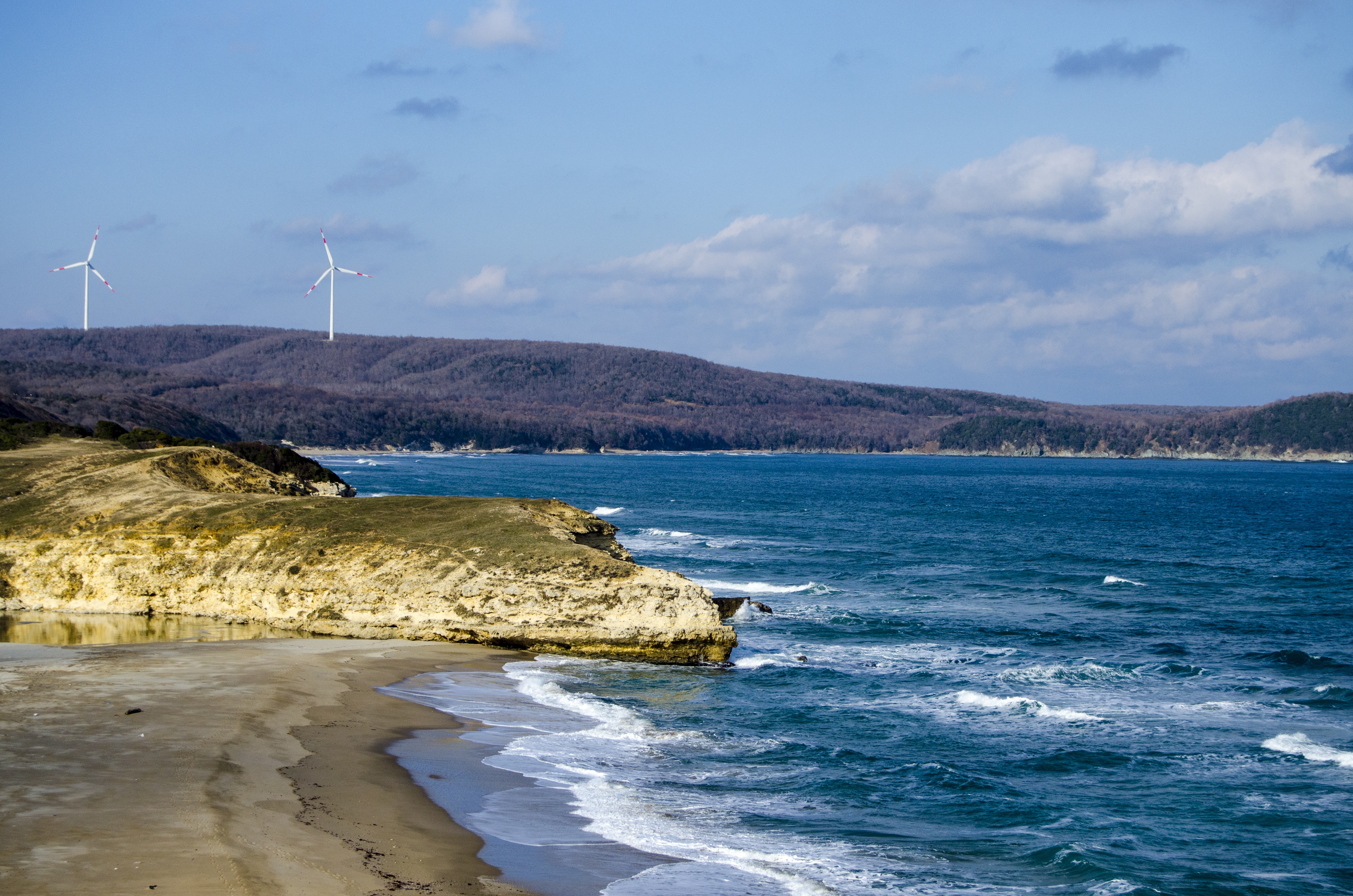 Küstenabschnitt in der Türkei mit Windrädern im Hintergrund.