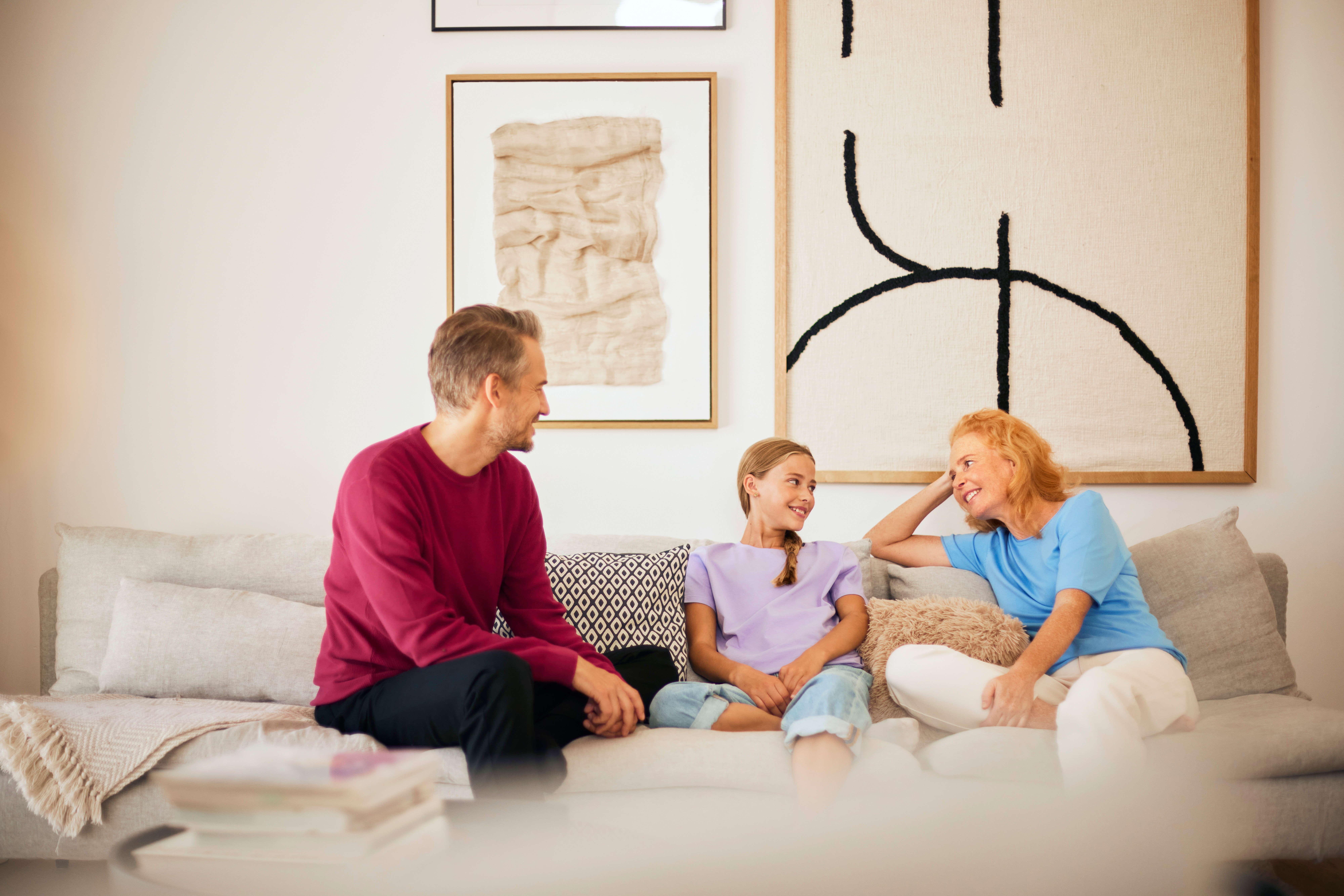 Eine Familie sitzt im Wohnzimmer und verbringt Familienzeit mit Gesprächen über Strom und Gas des Stromanbieters NEW Energie.