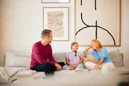 Familienzeit NEW Energie Eine Familie sitzt im Wohnzimmer und verbringt Familienzeit mit Gesprächen über Strom und Gas des Stromanbieters NEW Energie.
