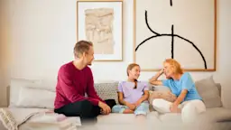Familienzeit NEW Energie Eine Familie sitzt im Wohnzimmer und verbringt Familienzeit mit Gesprächen über Strom und Gas des Stromanbieters NEW Energie.
