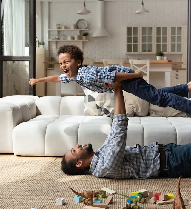 Vater und Sohn im Wohnzimmer Vater und Sohn liegen auf dem Wohnzimmerboden und spielen. Die Energie kommt von NEW Energie.