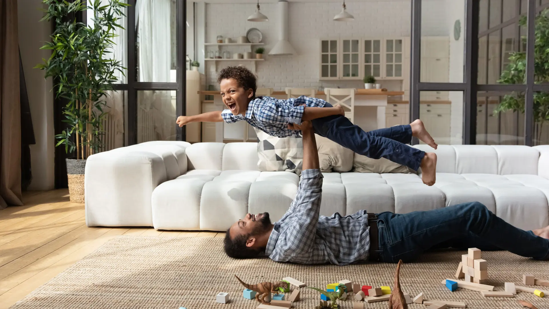 Vater und Sohn spielen im Wohnzimmer und freuen sich Energiekosten zu senken.