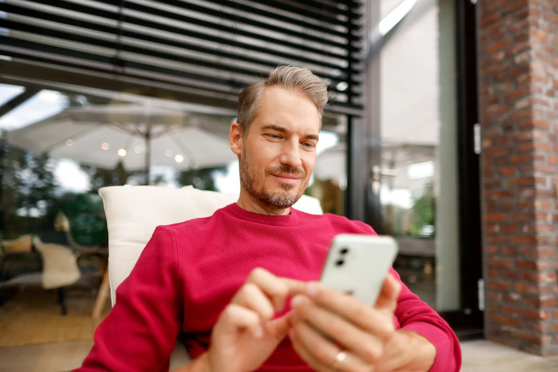 Ein Kunde der NEW Energie liegt auf einer Gartenliege mit einem Smartphone in der Hand und informiert sich über Anliegen bei dem Energieversorger.