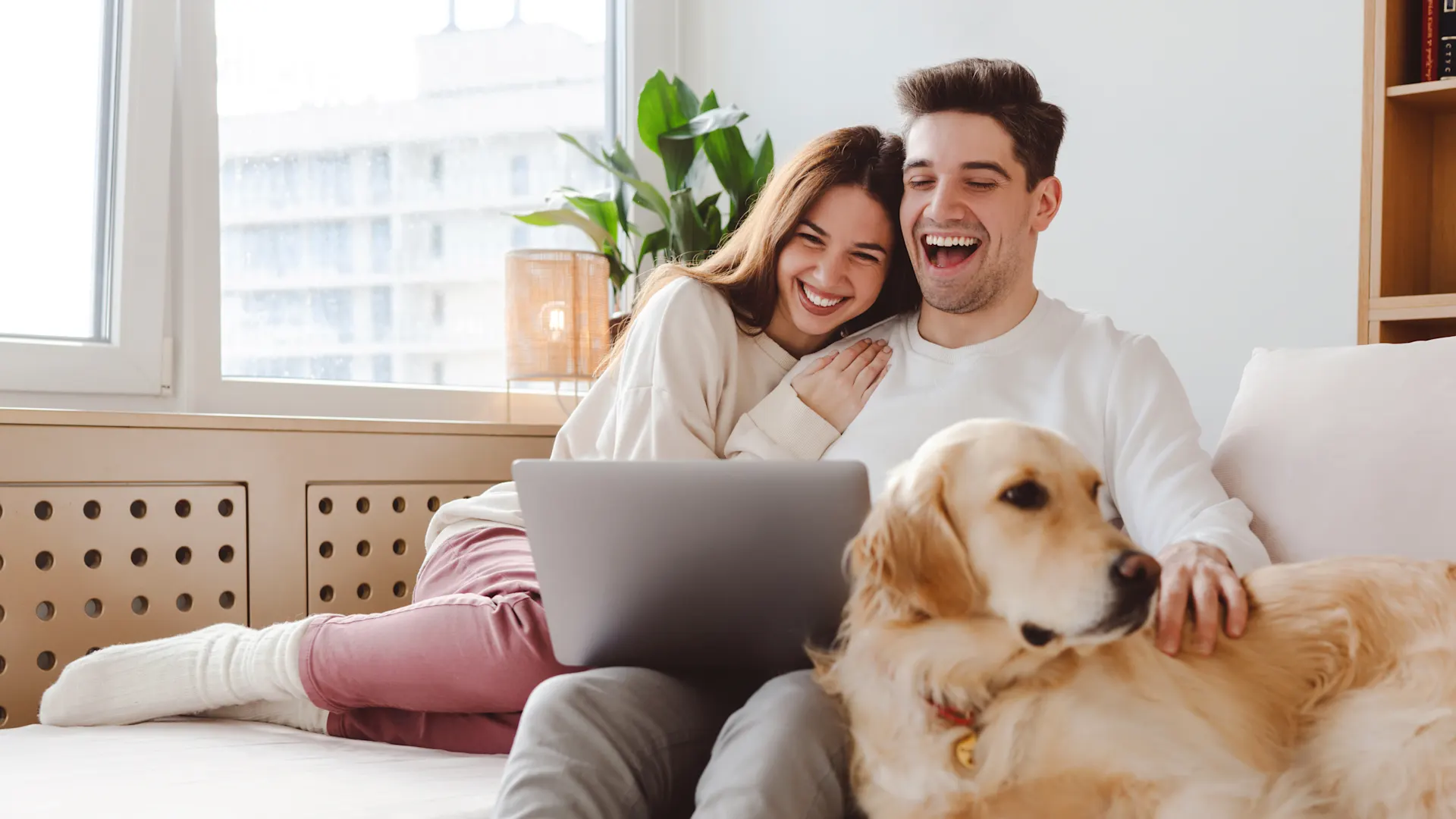 Günstige Angebote von der NEW Energie Ein Paar sitzt lächend auf dem Sofa und schauen sich die Tarife der NEW Energie an.