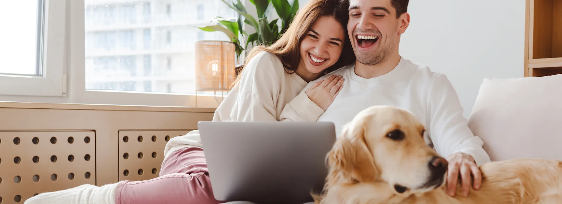 Günstige Angebote von der NEW Energie Ein Paar sitzt lächend auf dem Sofa und schauen sich die Tarife der NEW Energie an.