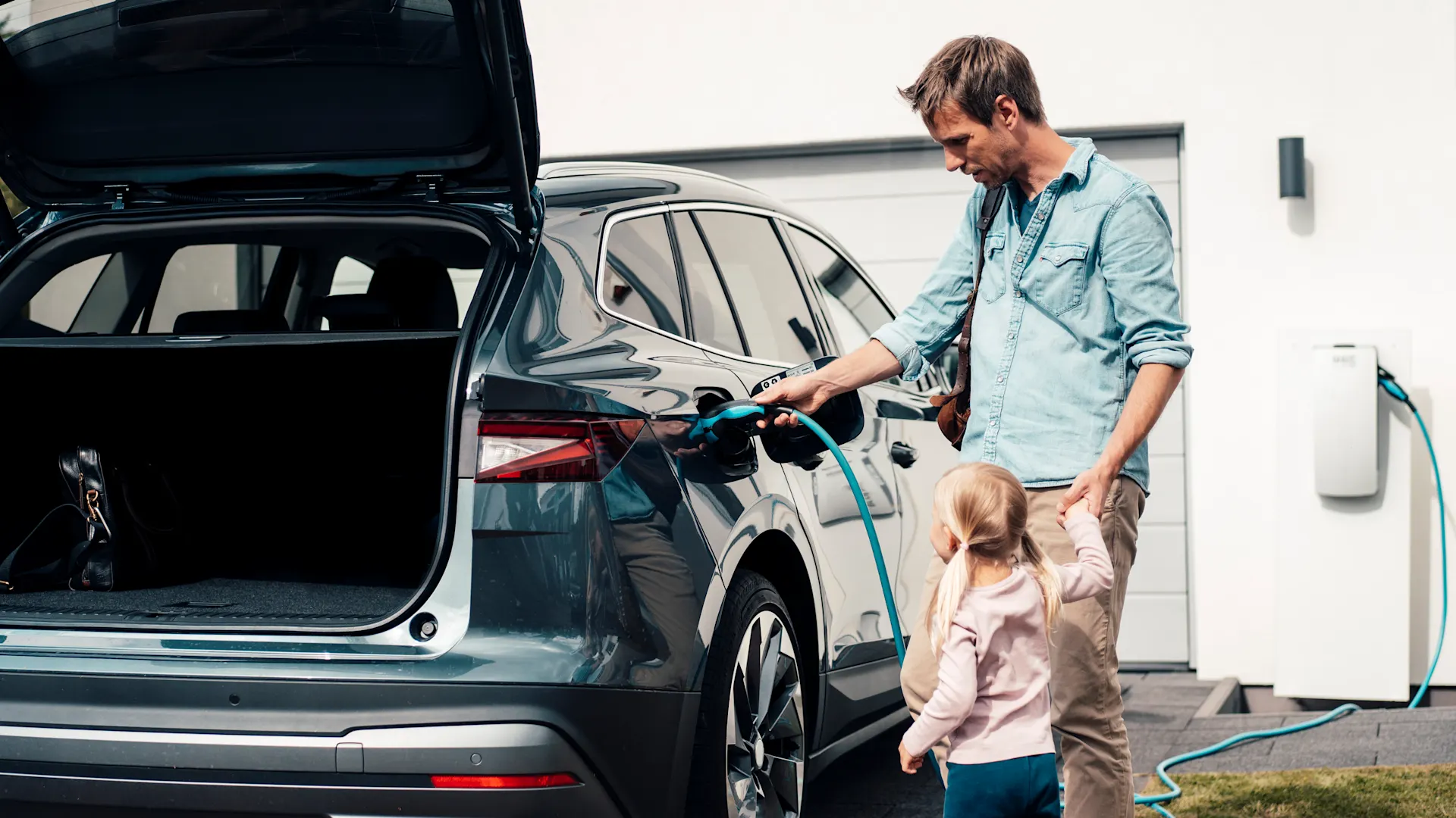 Wallbox am Zuhause Ein Mann steckt ein Ladekabel in sein E-Auto. Sein Auto wird Strom von der NEW Energie geladen.