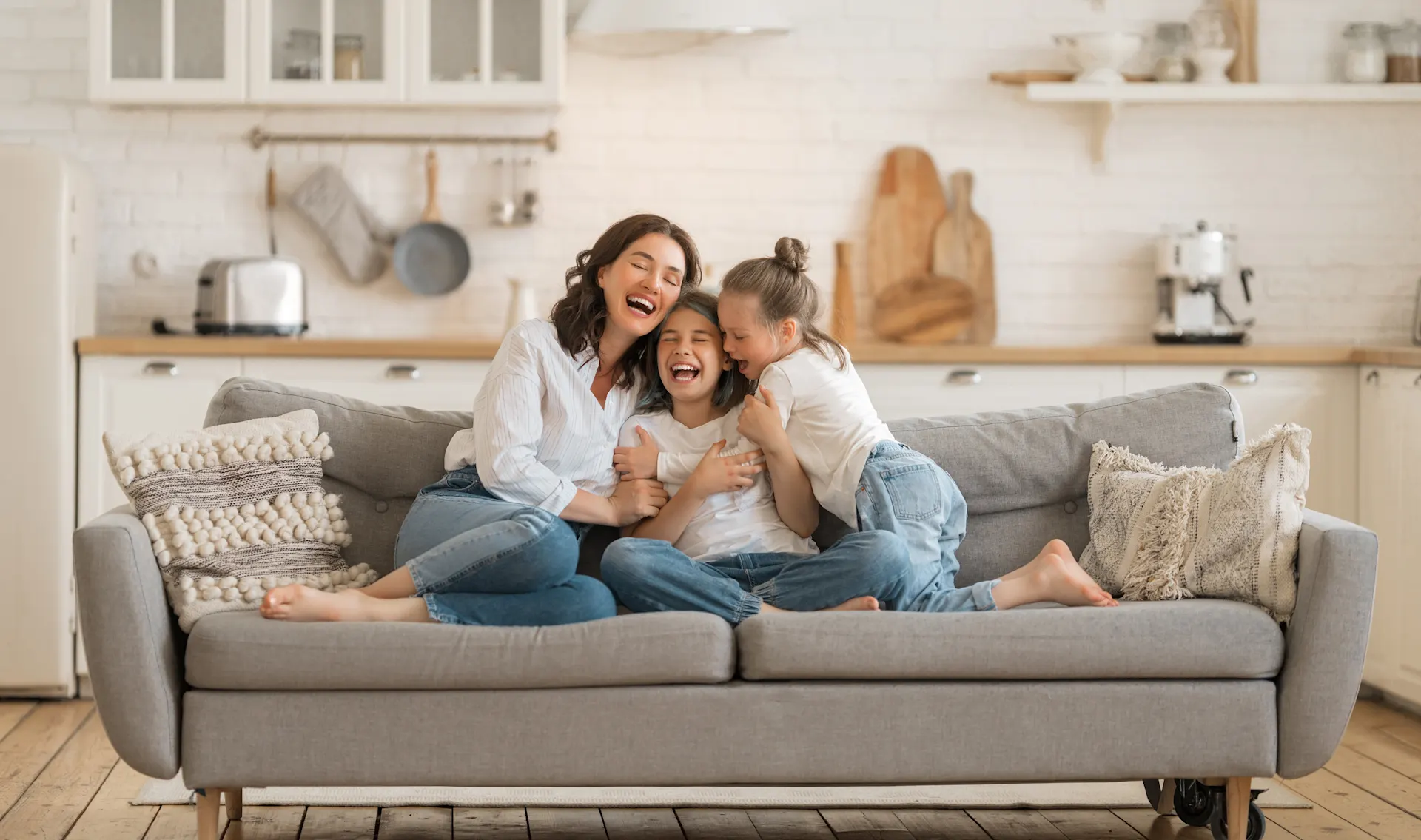 Mutter sitzt mit zwei Kindern auf dem Sofa Familienzeit auf dem Sofa mit Mutter und zwei Kindern. Die Mutter albert mit ihren Kindern herum.