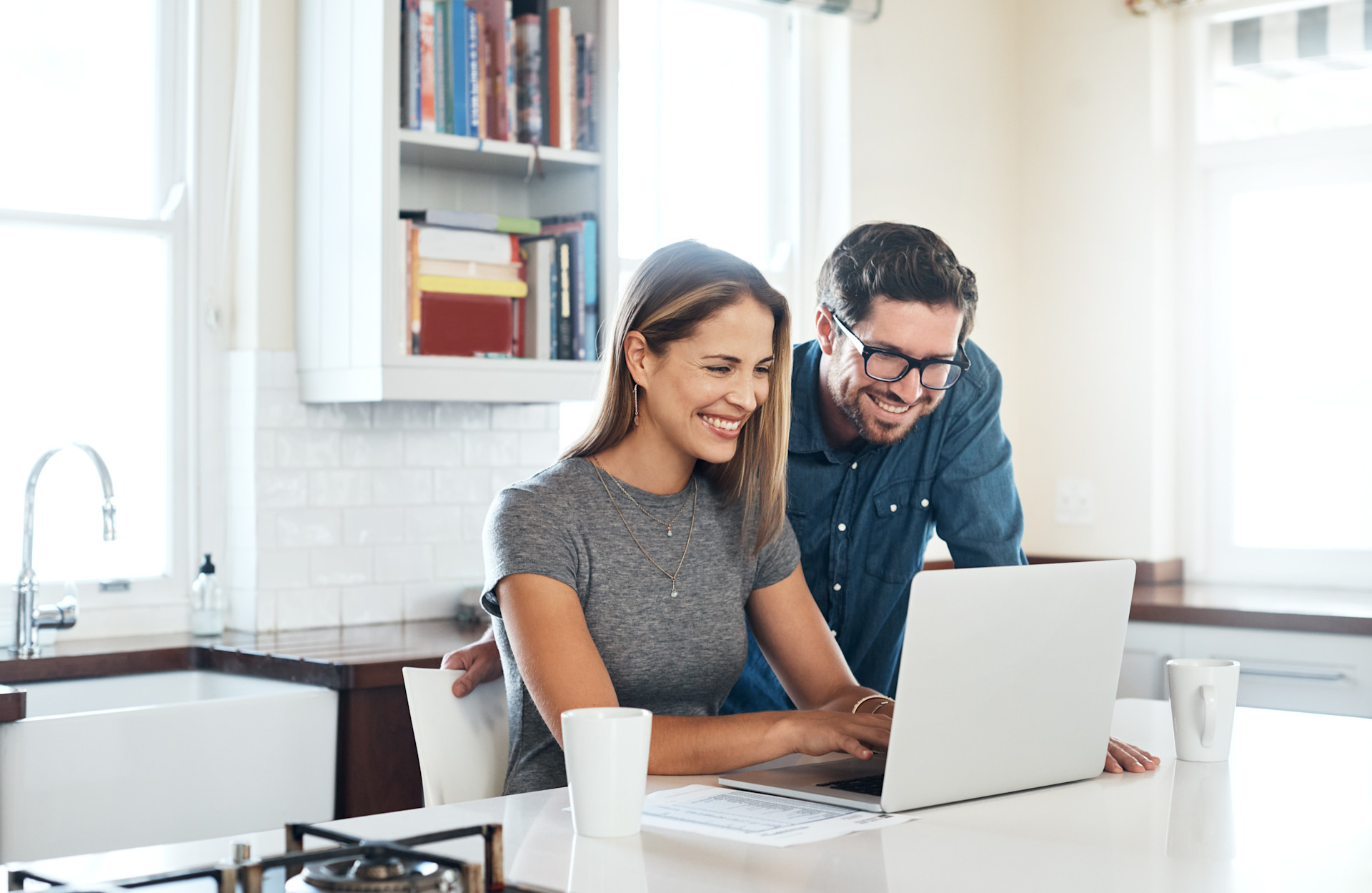 Ein Mann und eine Frau sitzen an einem Laptop und vergleichen die Strompreise der NEW Energie.