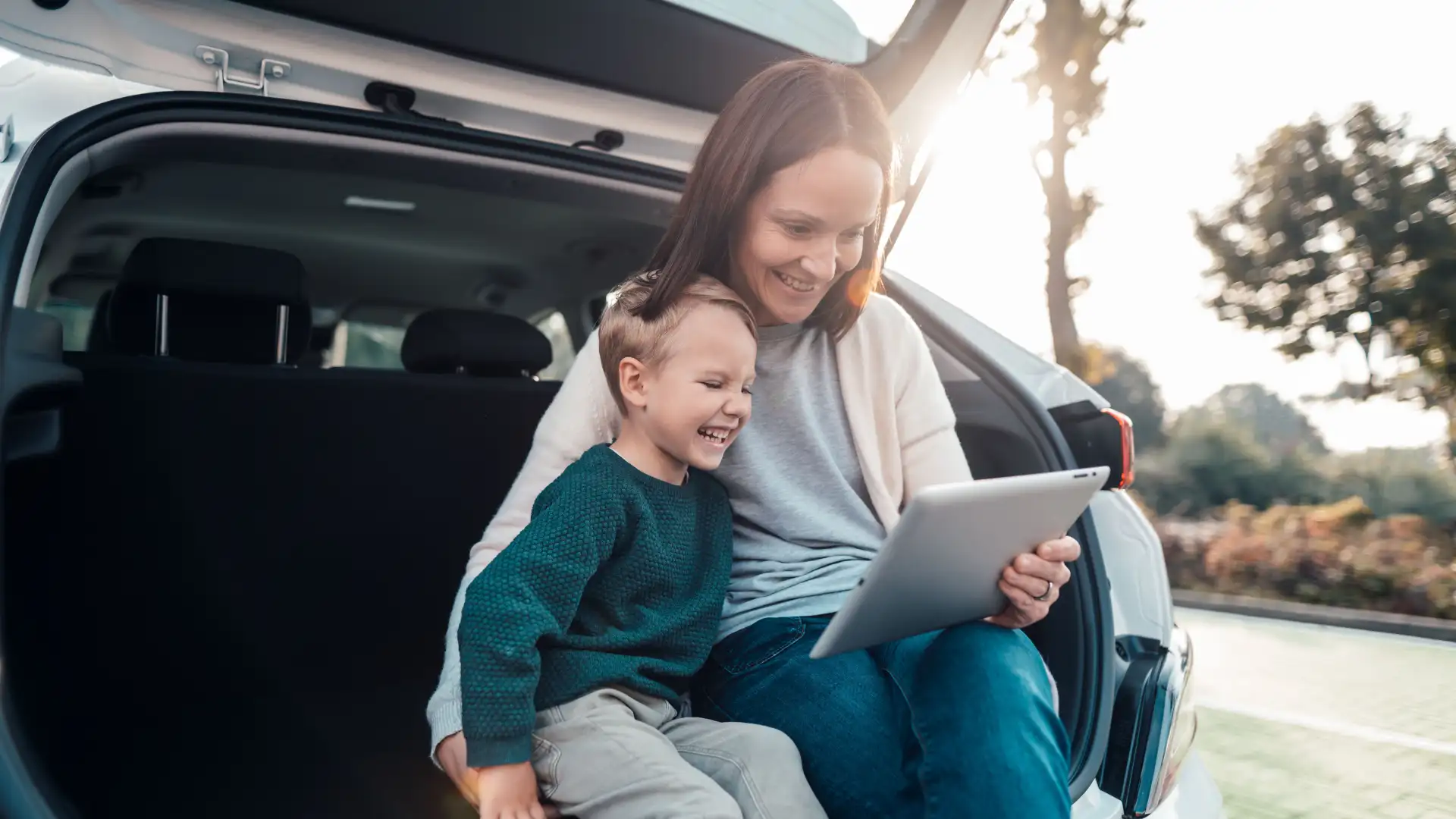 Familie parkt auf einem öffentlichen Parkplatz und informiert sich mit einem Tablet über den Energieversorger.