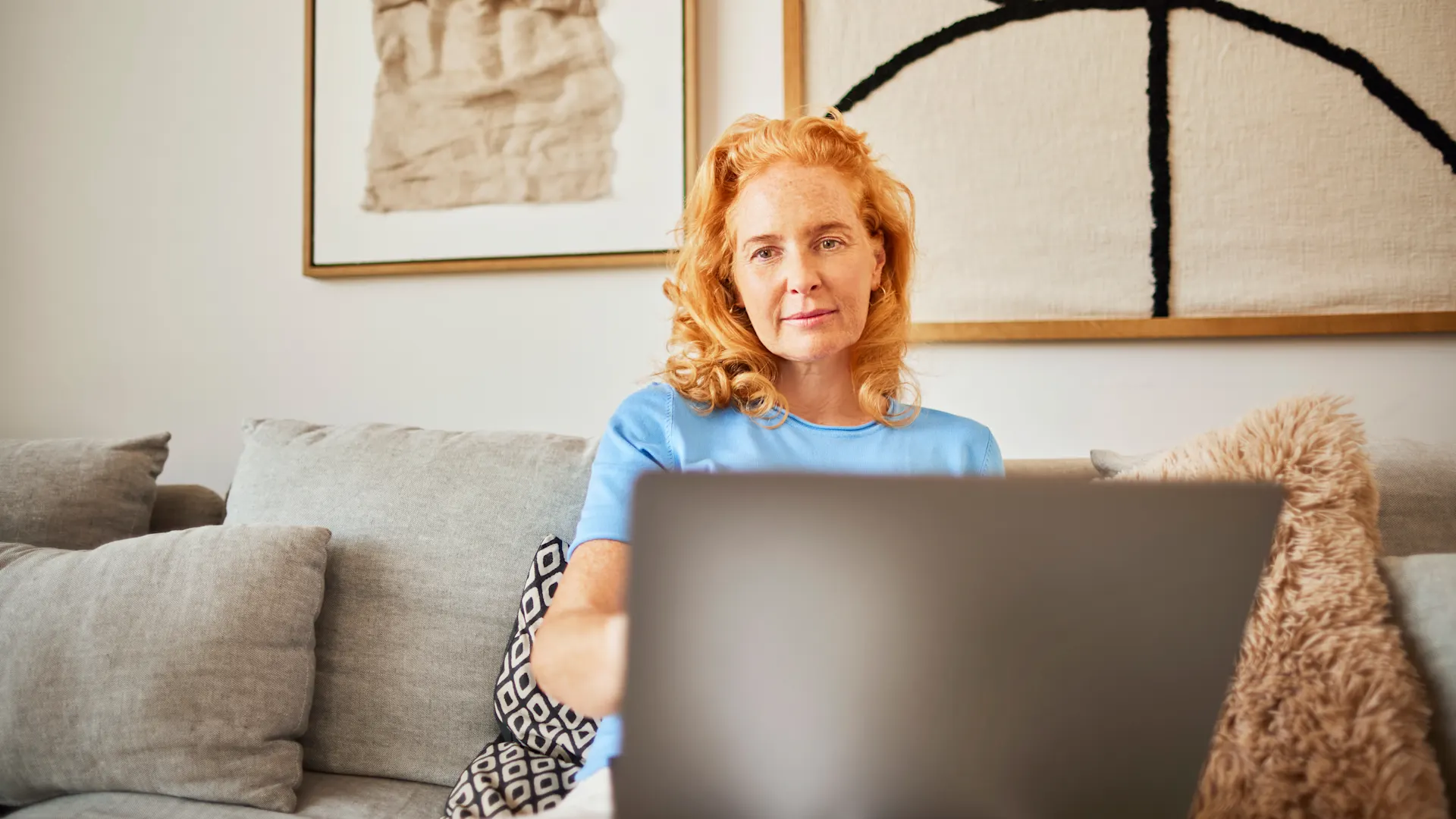 Auswahl günstiger Energie Eine Frau sitzt mit ihrem Laptop auf dem Sofa und informiert sich über die Auswahl an günstiger Energie der NEW Energie.