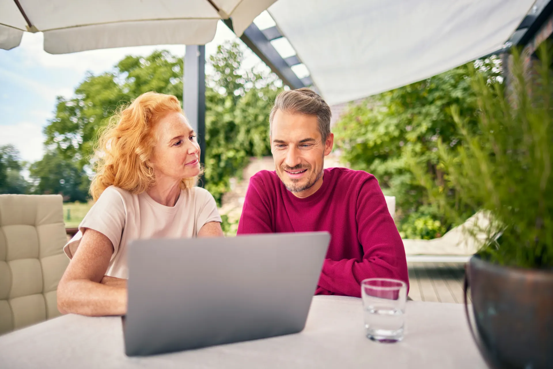 Kunden der NEW Energie sitzen mit einem Laptop im Garten und informieren sich über die sichere Versorgung, günstigen Tarife und die günstige Energie des Energieversorgers.