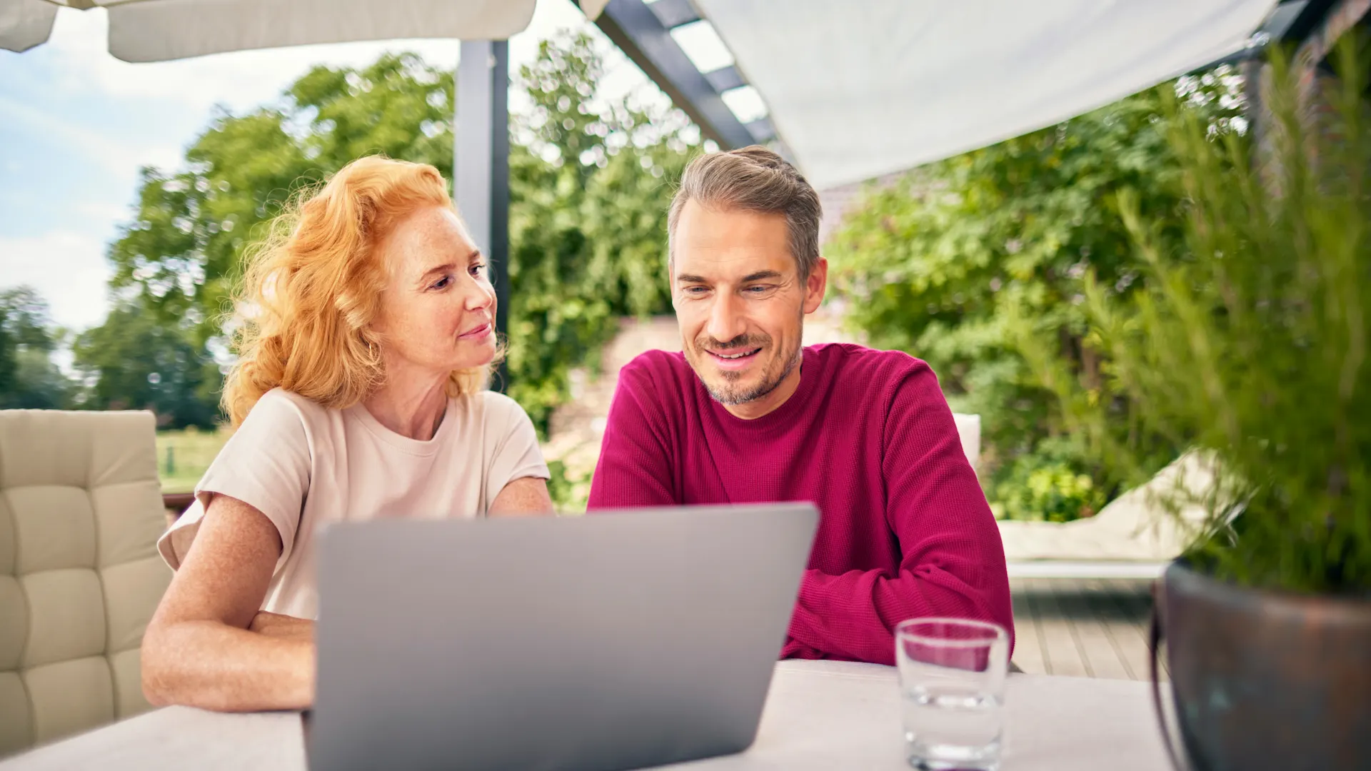 Ehepaar vergleicht Tarife der NEW Energie Kunden der NEW Energie sitzen mit einem Laptop am Gartentisch und informieren sich über die sichere Versorgung, günstigen Tarife und die günstige Energie des Energieversorgers.