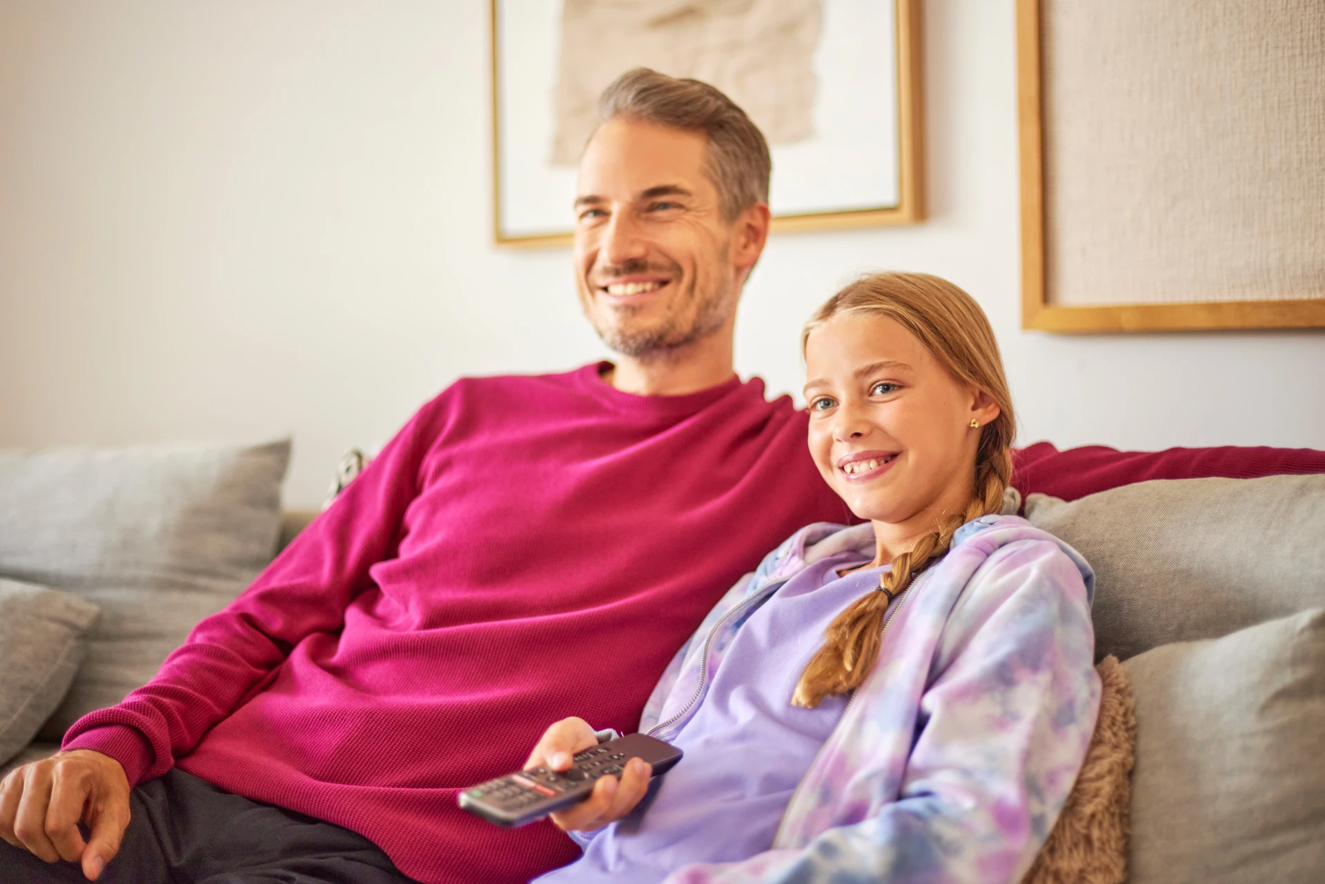 Kunden der NEW Energie verbringen gemeinsam mit der Familie Zeit vor dem TV und bedienen diesen mit einer Fernbedienung.