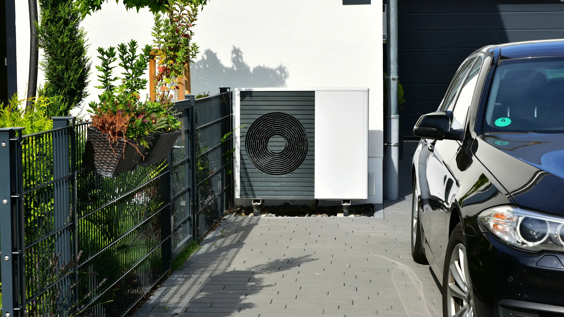 Wärmepumpe an der Garage Eine Wärmepumpe steht an einer Garage im Außenbereich.