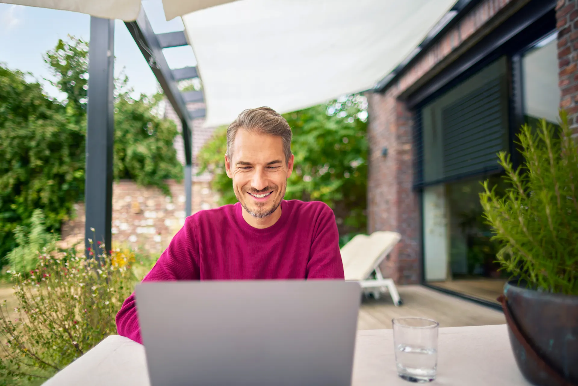 Ein Mann sitzt im Garten mit einem Laptop und informiert sich über die günstigen Tarife der NEW Energie. 