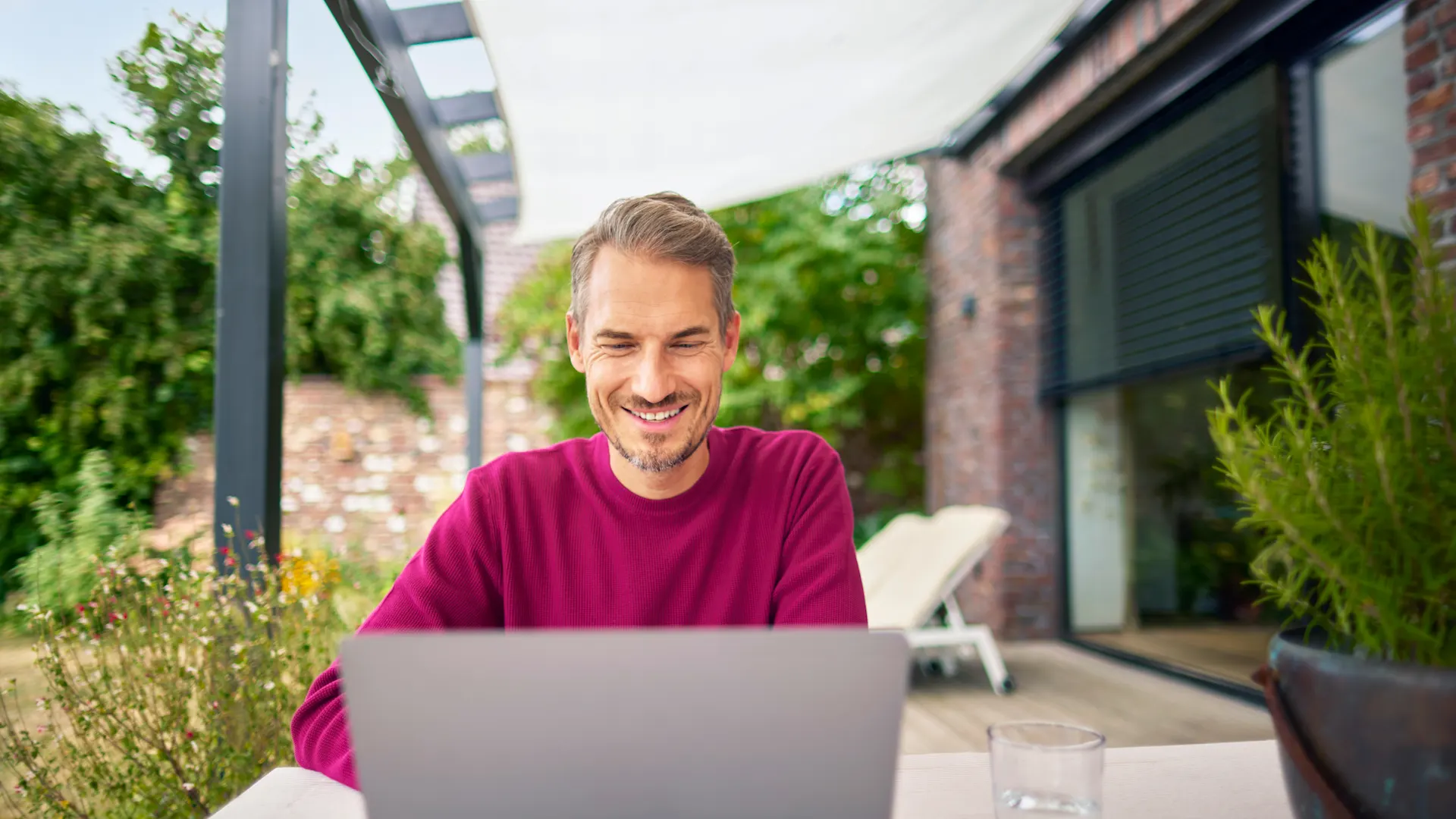 Tarifauswahl im Garten treffen Ein Mann sitzt im Garten mit einem Laptop und informiert sich über die günstigen Tarife der NEW Energie.