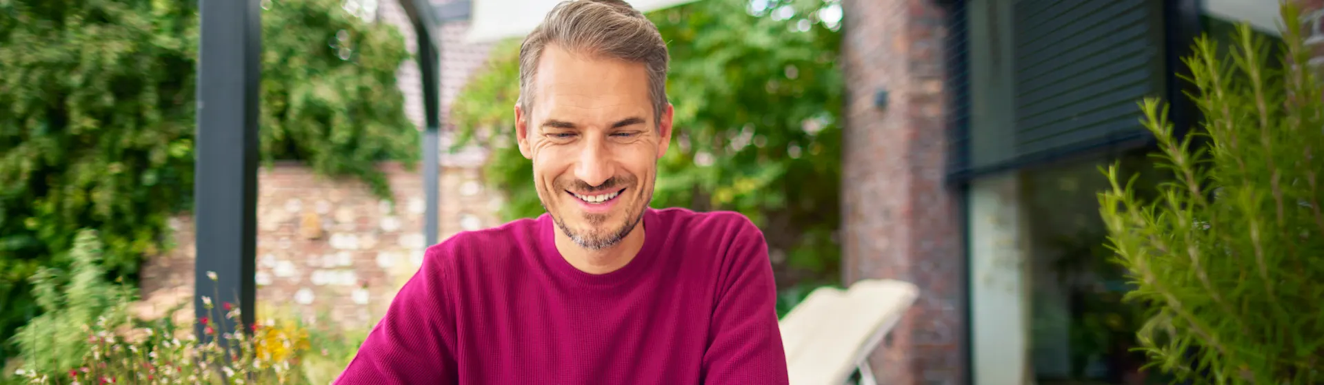 Tarifauswahl im Garten treffen Ein Mann sitzt im Garten mit einem Laptop und informiert sich über die günstigen Tarife der NEW Energie.
