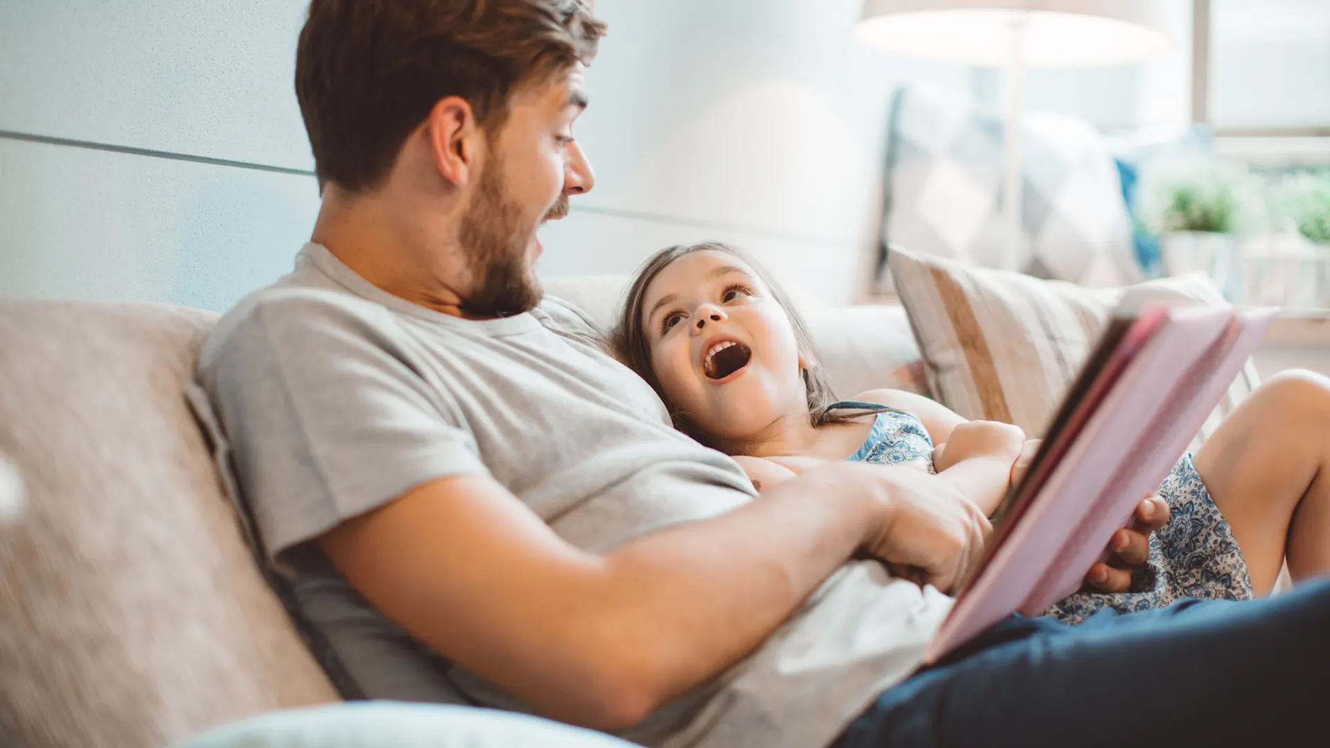 Vater mit Tochter auf dem Sofa mit Tablet Vater surft mit Tochter im Internet auf dem Tablet und sitzen dabei auf einem Sofa.