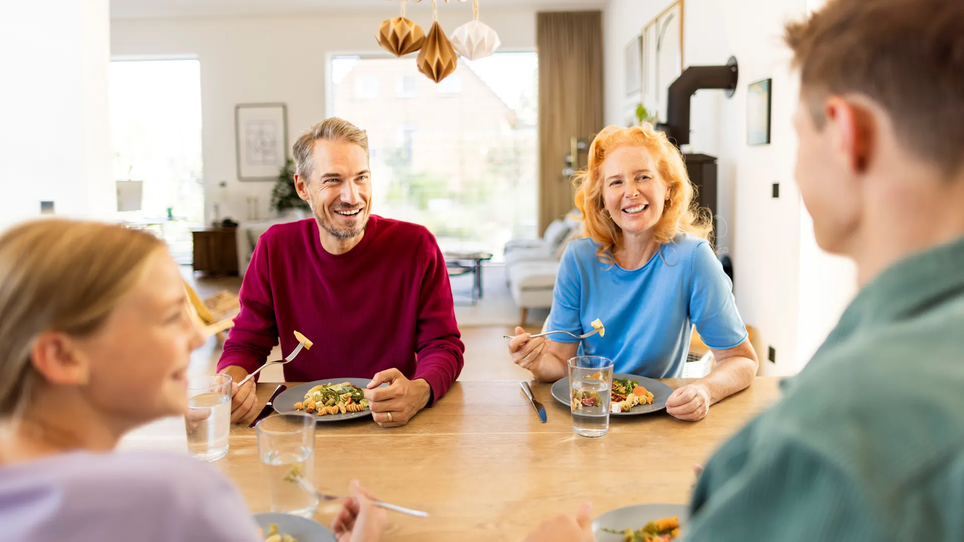Familienessen Eine Familie sitzt an einem Esstisch zum Familienessen und unterhält sich über die Stromtarife des Stromanbieters NEW Energie.