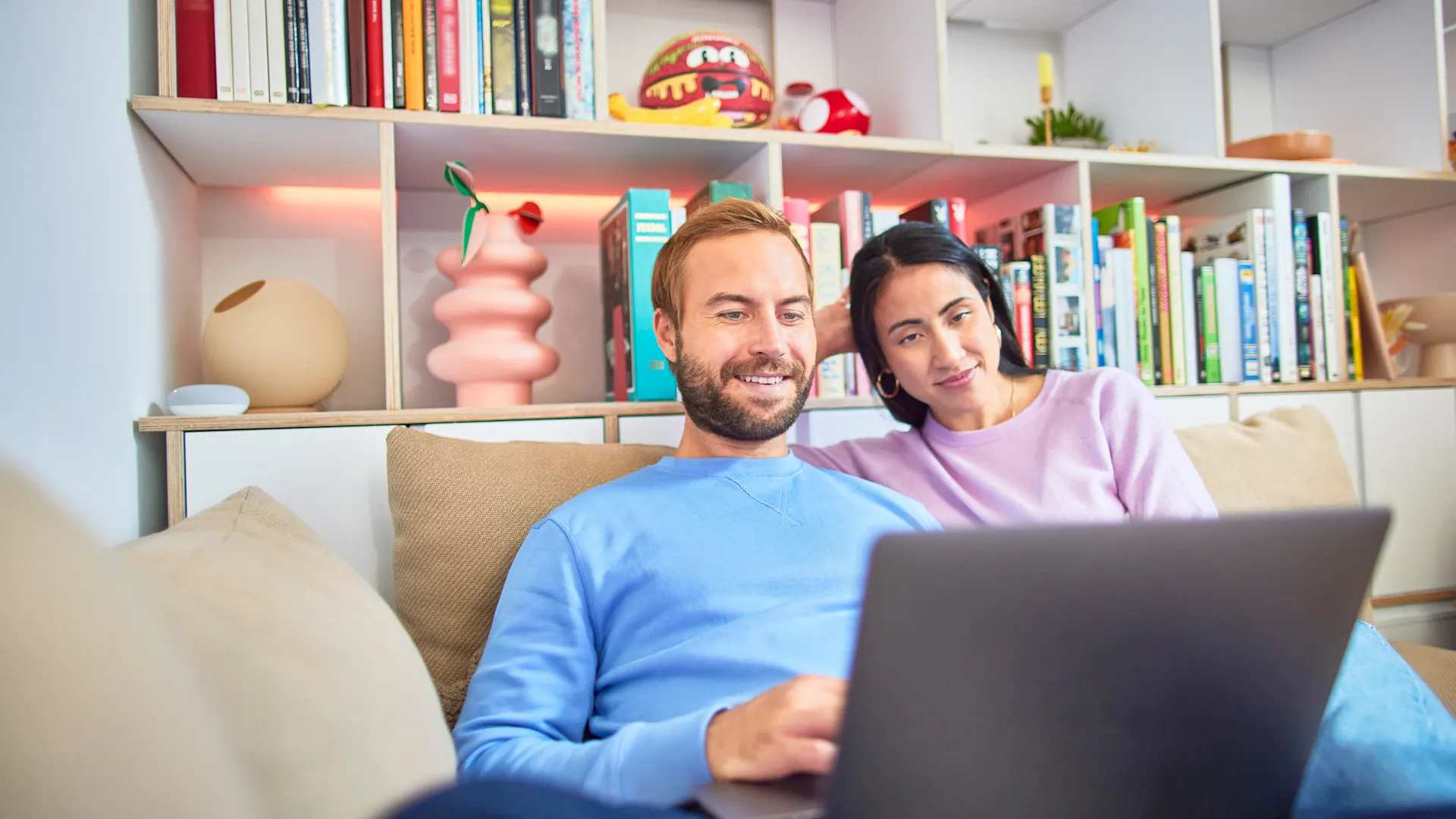 Familie an Laptop Ein Paar sitzt auf dem Sofa und vergleicht am Laptop Tarife der NEW Energie.