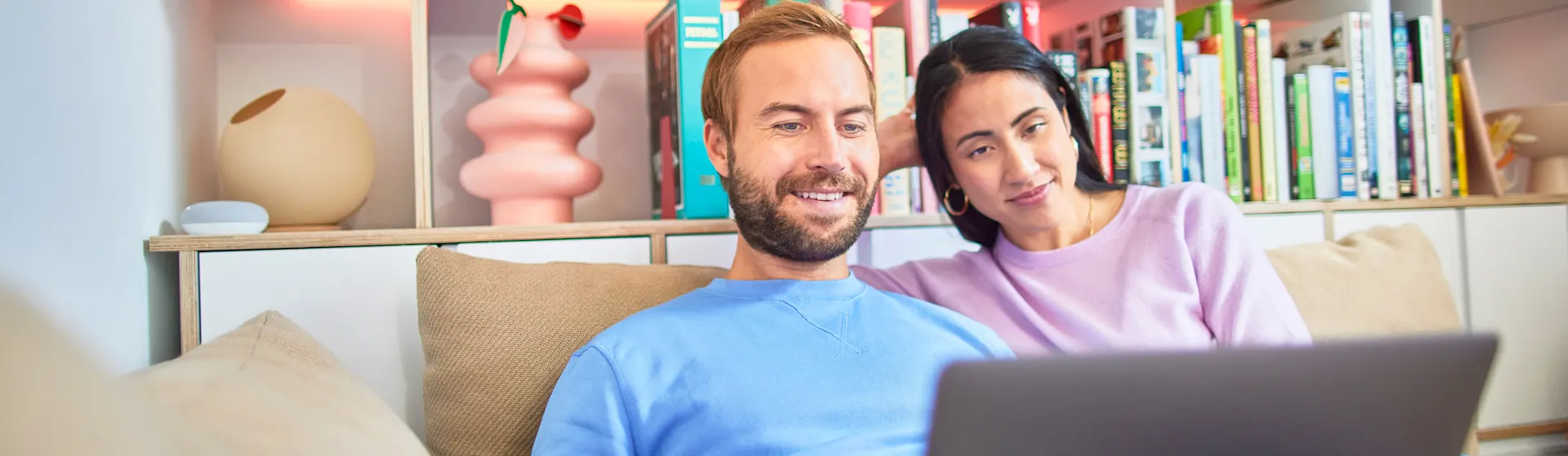 Familie an Laptop Ein Paar sitzt auf dem Sofa und vergleicht am Laptop Tarife der NEW Energie.