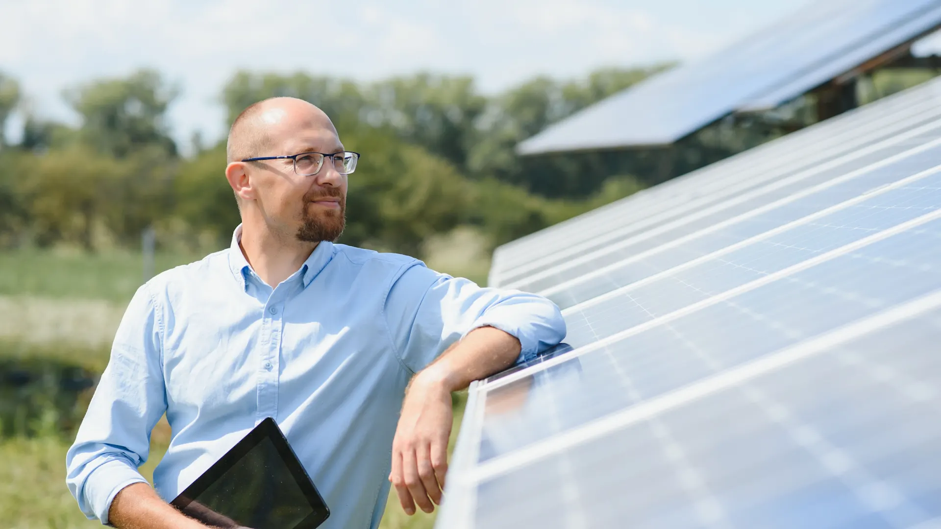 Mann steht vor großer PV-Anlage Ein Mann steht draußen neben einer großen Photovoltaikanlage der NEW Energie.