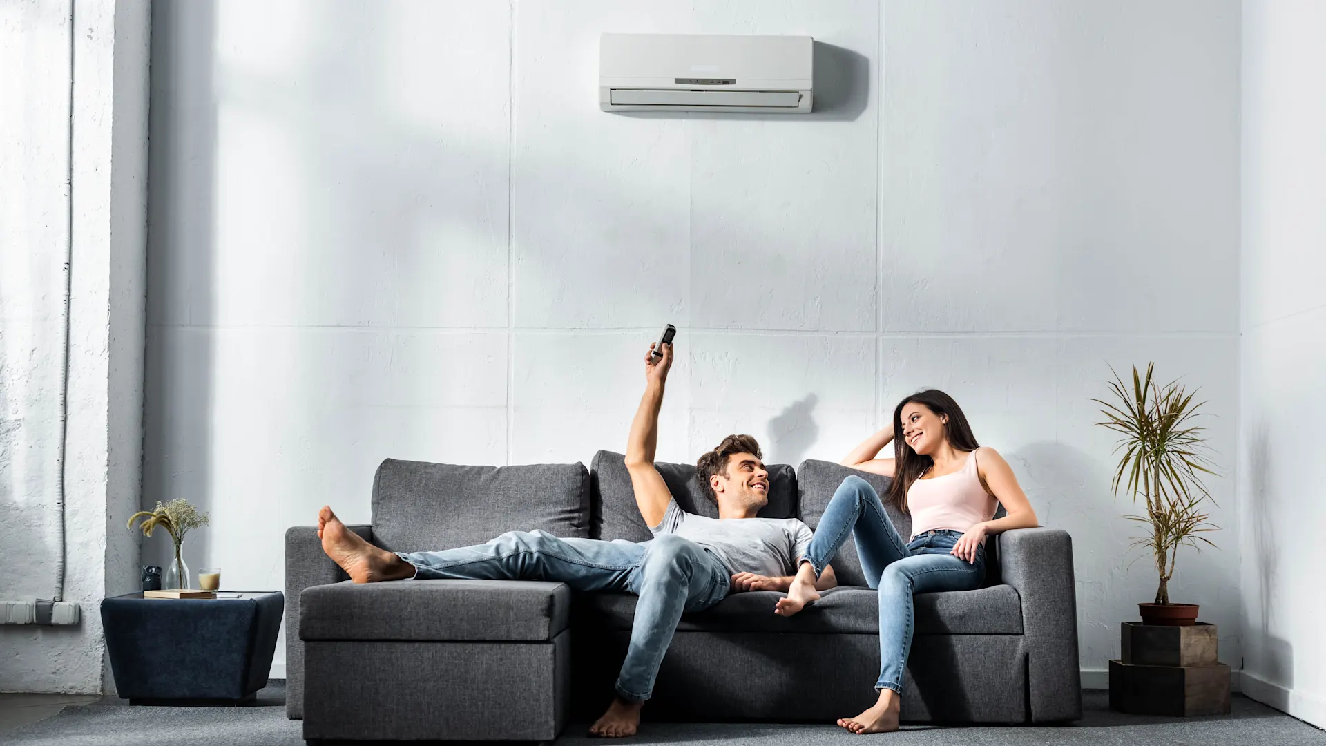 Luft-Luft Wärmepumpe Zwei Personen sitzen im Wohnzimmer auf einem dunklem Sofa und nutzen energieeffiziente Technik – mit Strom von NEW Energie.