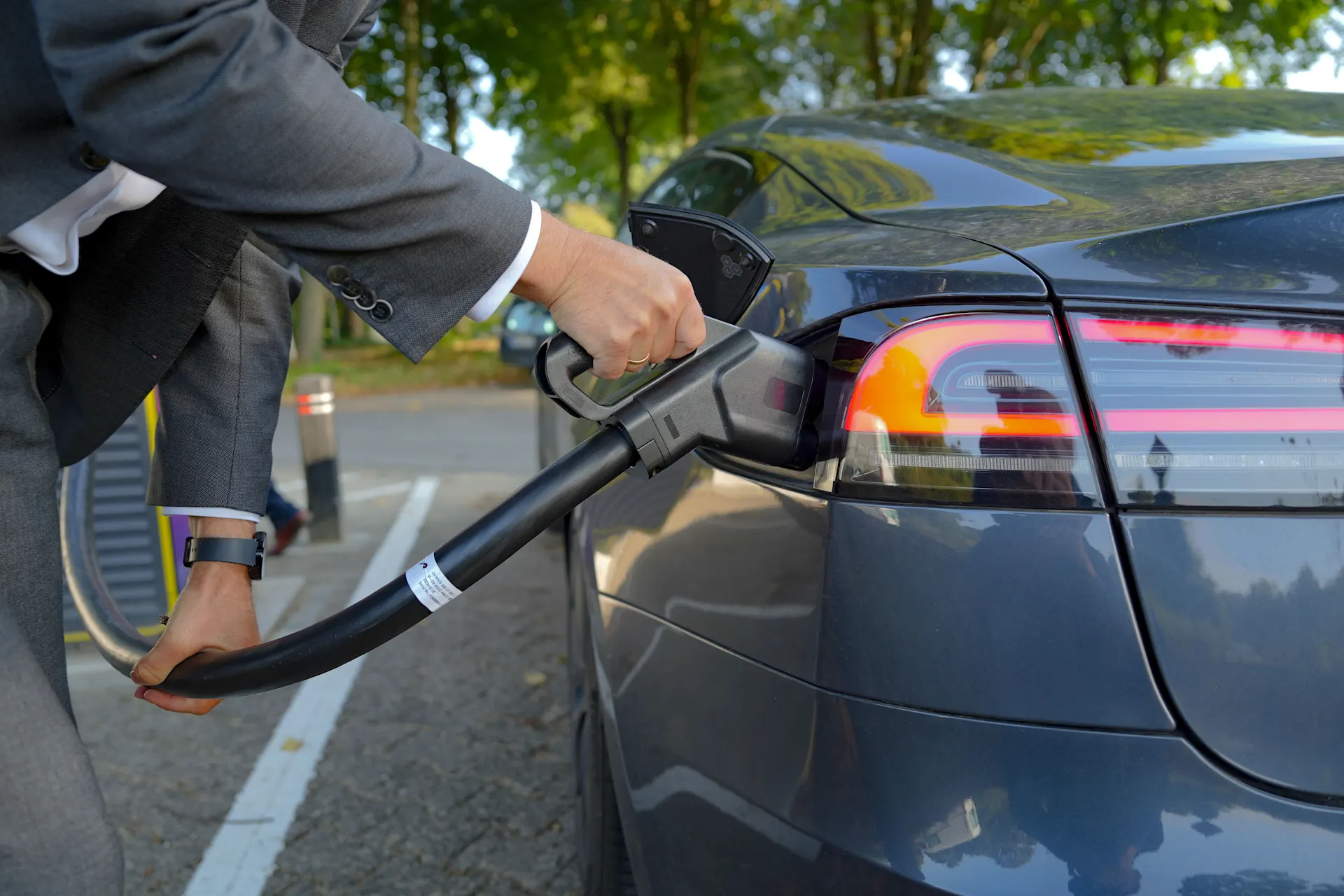 Ein Mann im Anzug lädt sein E-Auto an einer Ladesäule der NEW Energie. 
