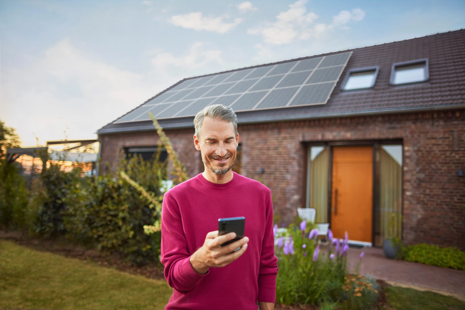 Ein Mann steht in einem Garten und informiert sich über das Thema Stromerzeugung bei Photovoltaikanlagen bei seinem Energieversorger NEW Energie.
