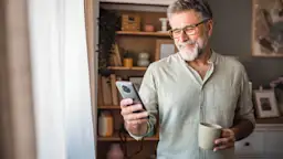 Rundum-sorglos-Service bei der NEW Energie Ein Mann informiert sich an seinem Smartphone über den guten Wechselservice bei der NEW Energie.