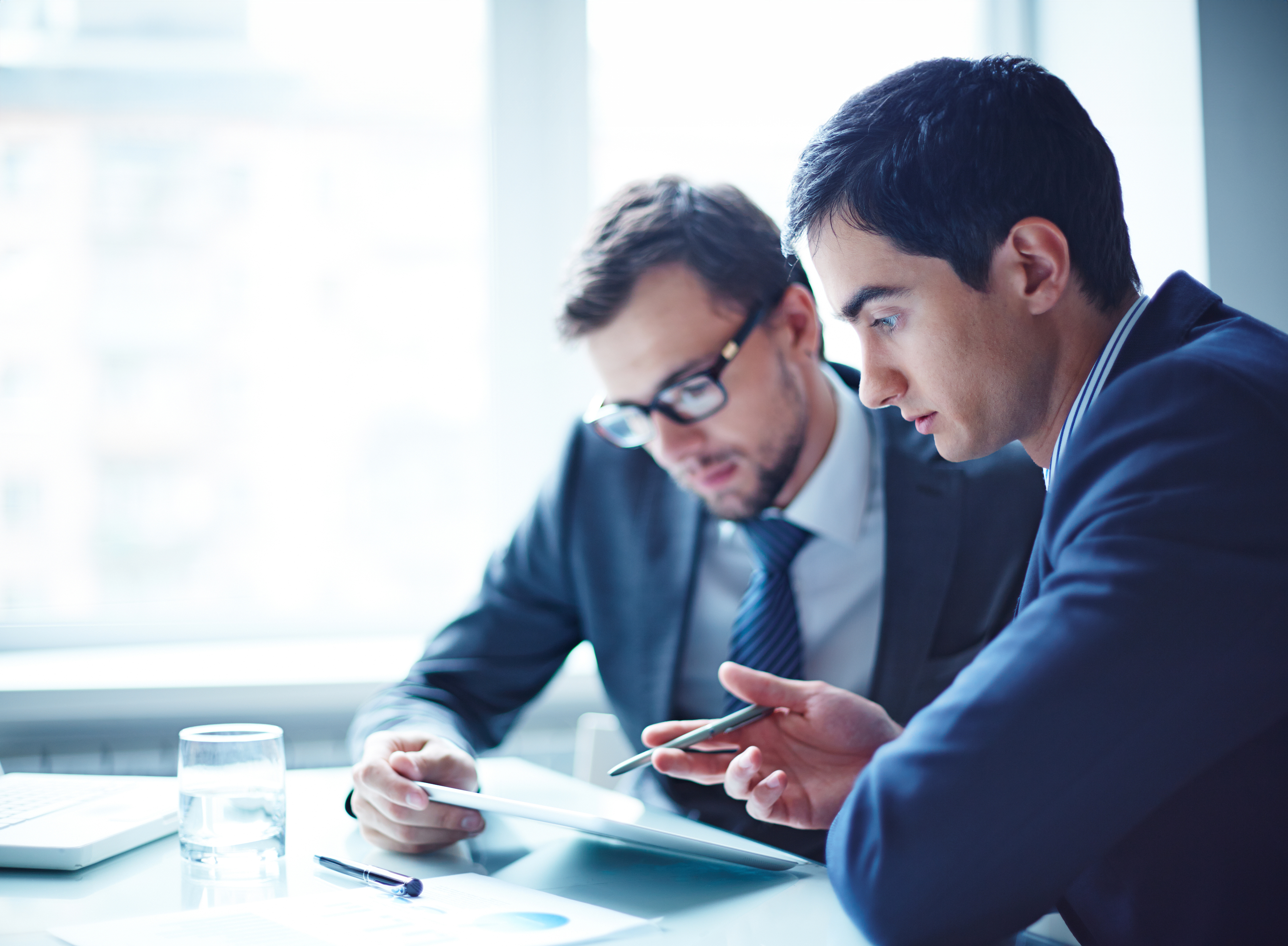 Zwei Männer sitzen zusammen an einem Schreibtisch und schauen sich gemeinsam einen Stromvertrag der NEW Energie an.