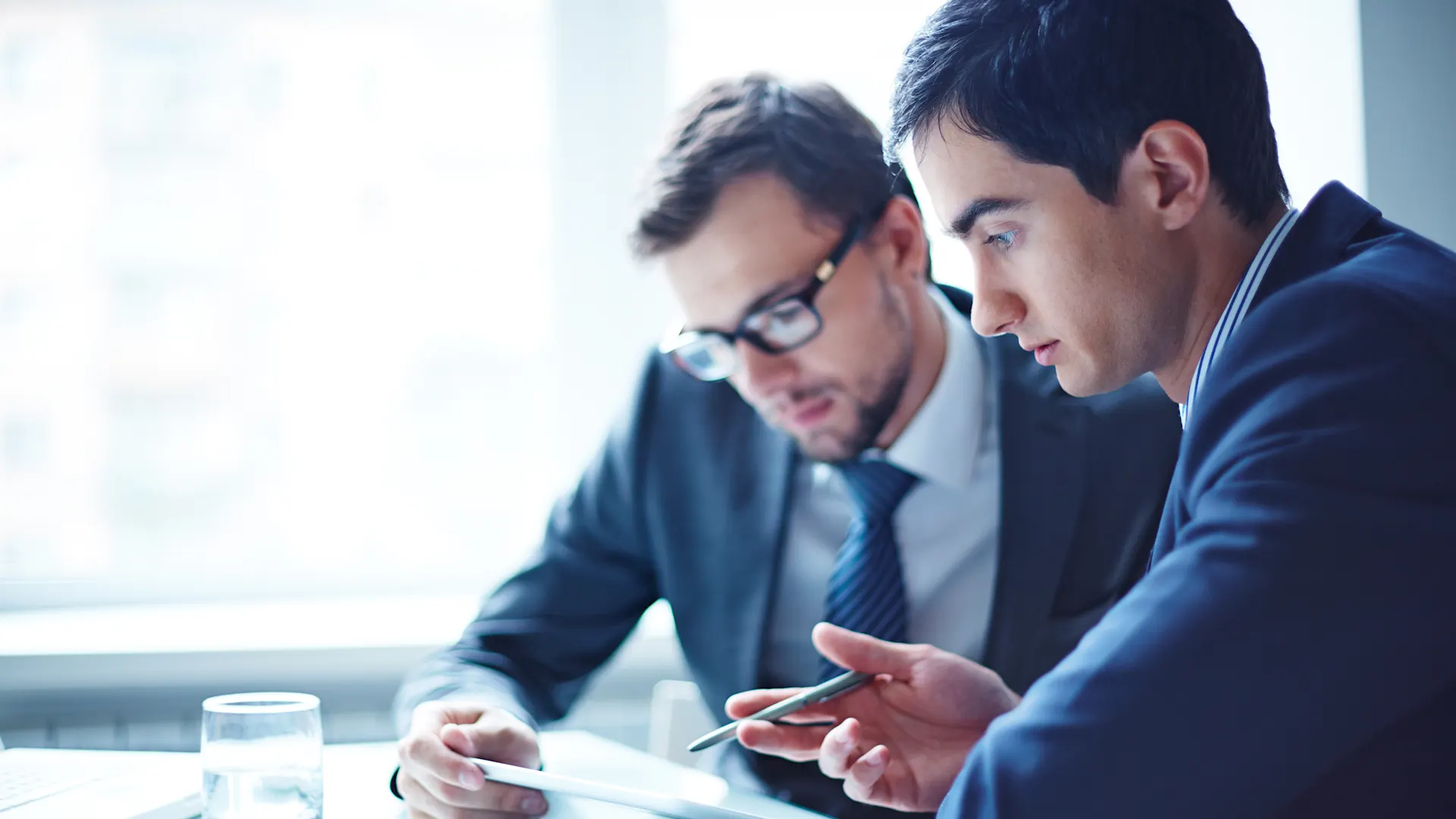Zwei Männer arbeiten an einem Stromvertrag Zwei Männer sitzen zusammen an einem Schreibtisch und schauen sich gemeinsam einen Stromvertrag der NEW Energie an.
