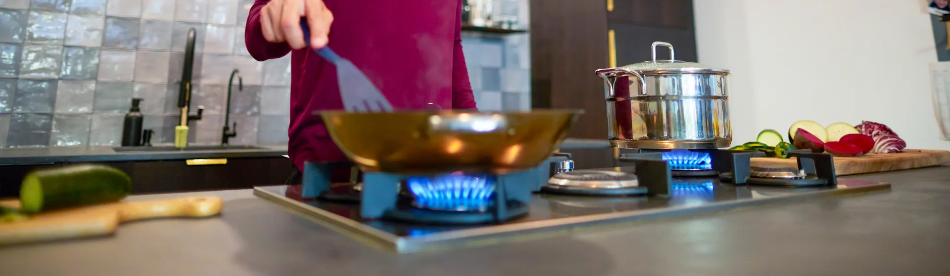 Abendessen zubereiten mit der NEW Energie Ein Mann bereitet das Abendessen auf einem Gasherd vor, welcher durch günstiges Ökogas der NEW Energie betrieben wird.