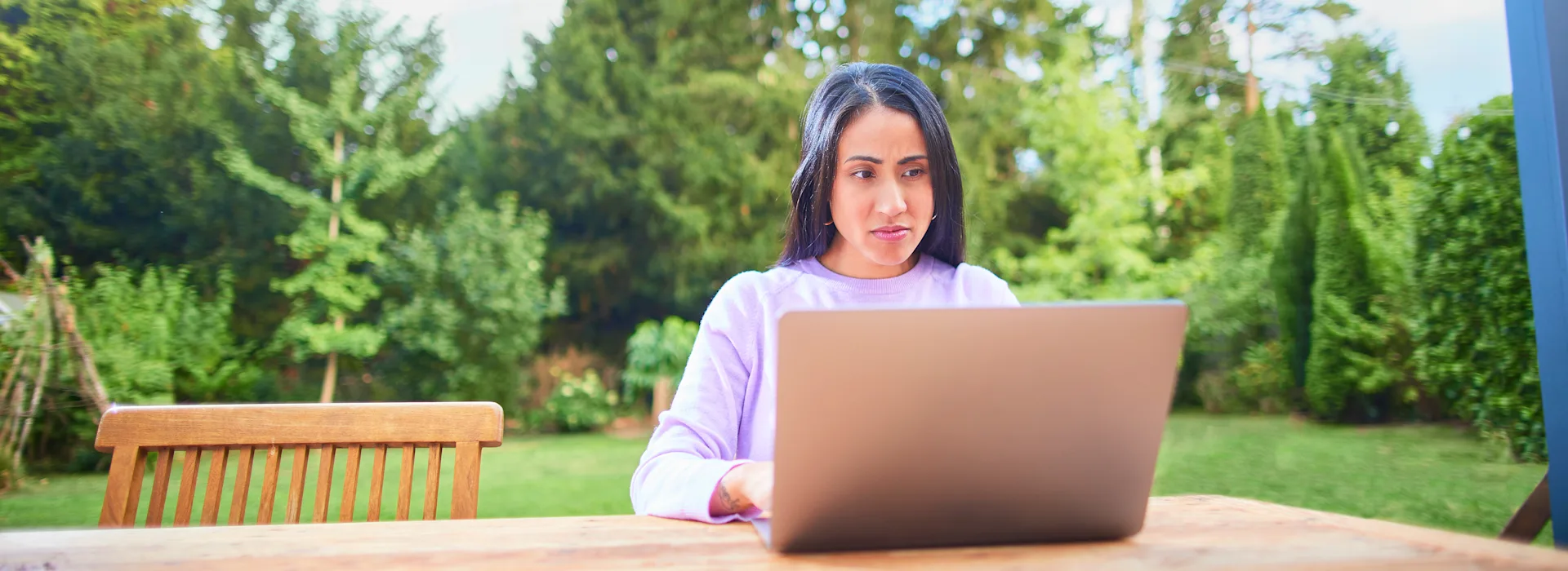 Frau am Laptop bearbeitet Ihren Tarif Eine Frau sitzt mit einem Laptop im Garten und informiert sich über die NEW Energie.